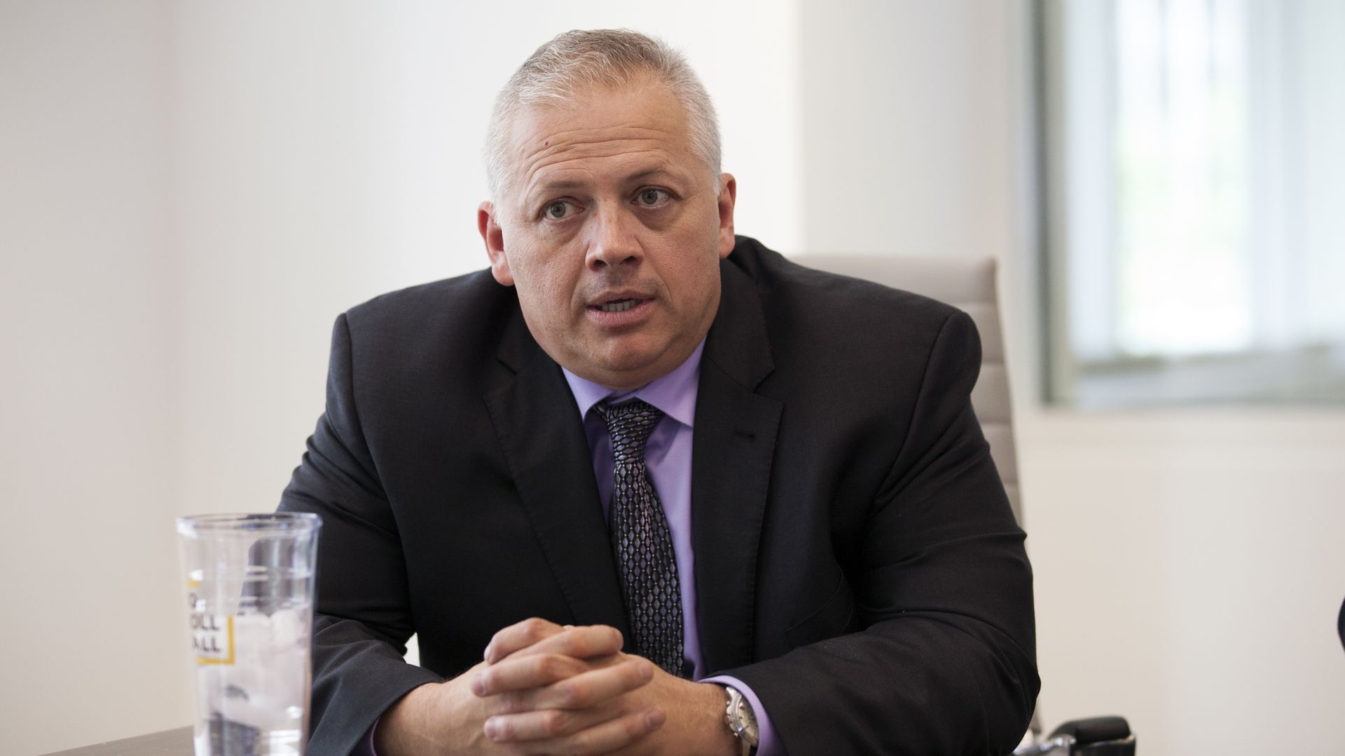 Photo of Denver Riggleman sitting at a table with his hands clasped