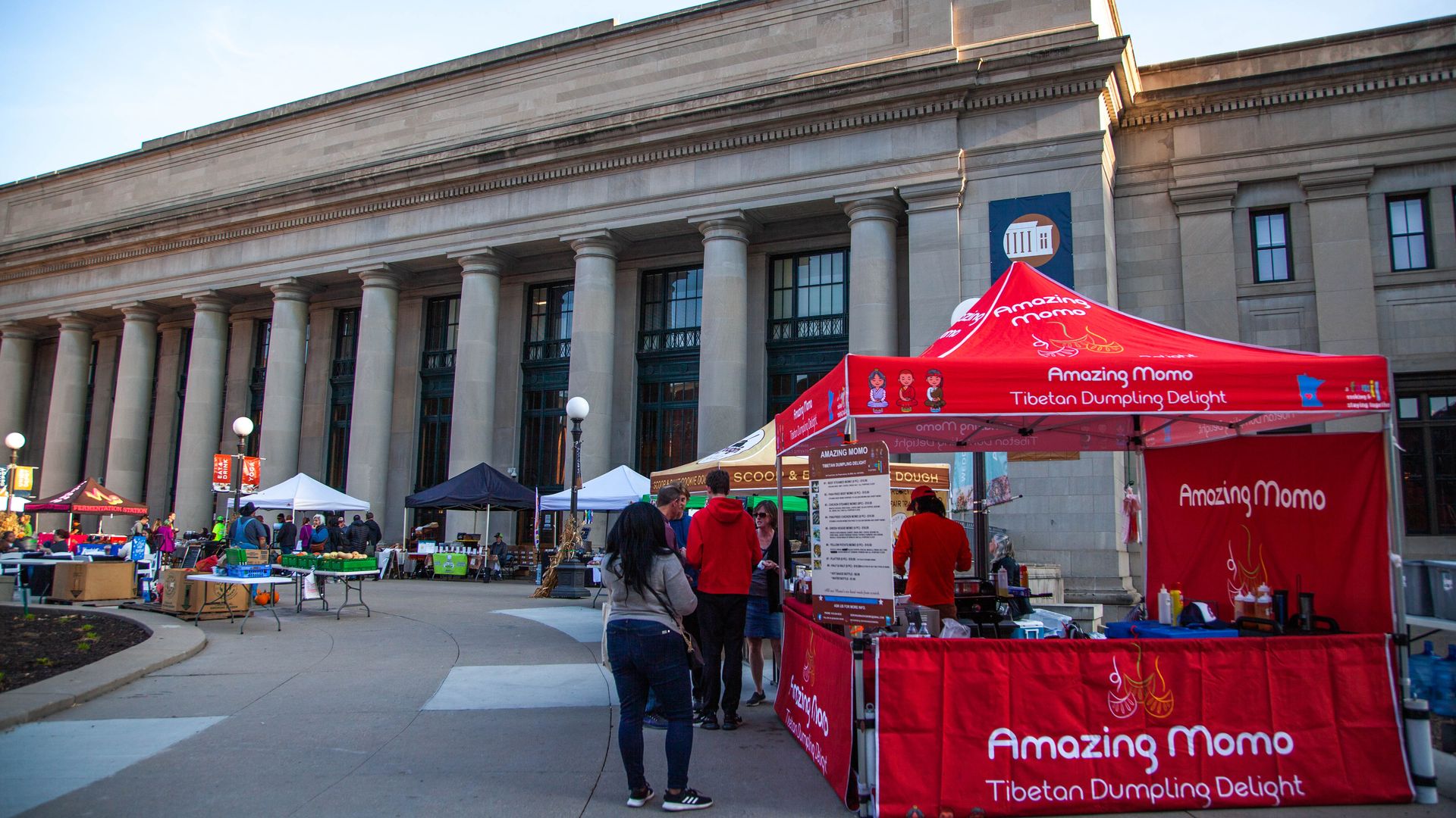 farmer's market vendor stands, including a red tent selling dumplings, in front of st. paul's union station