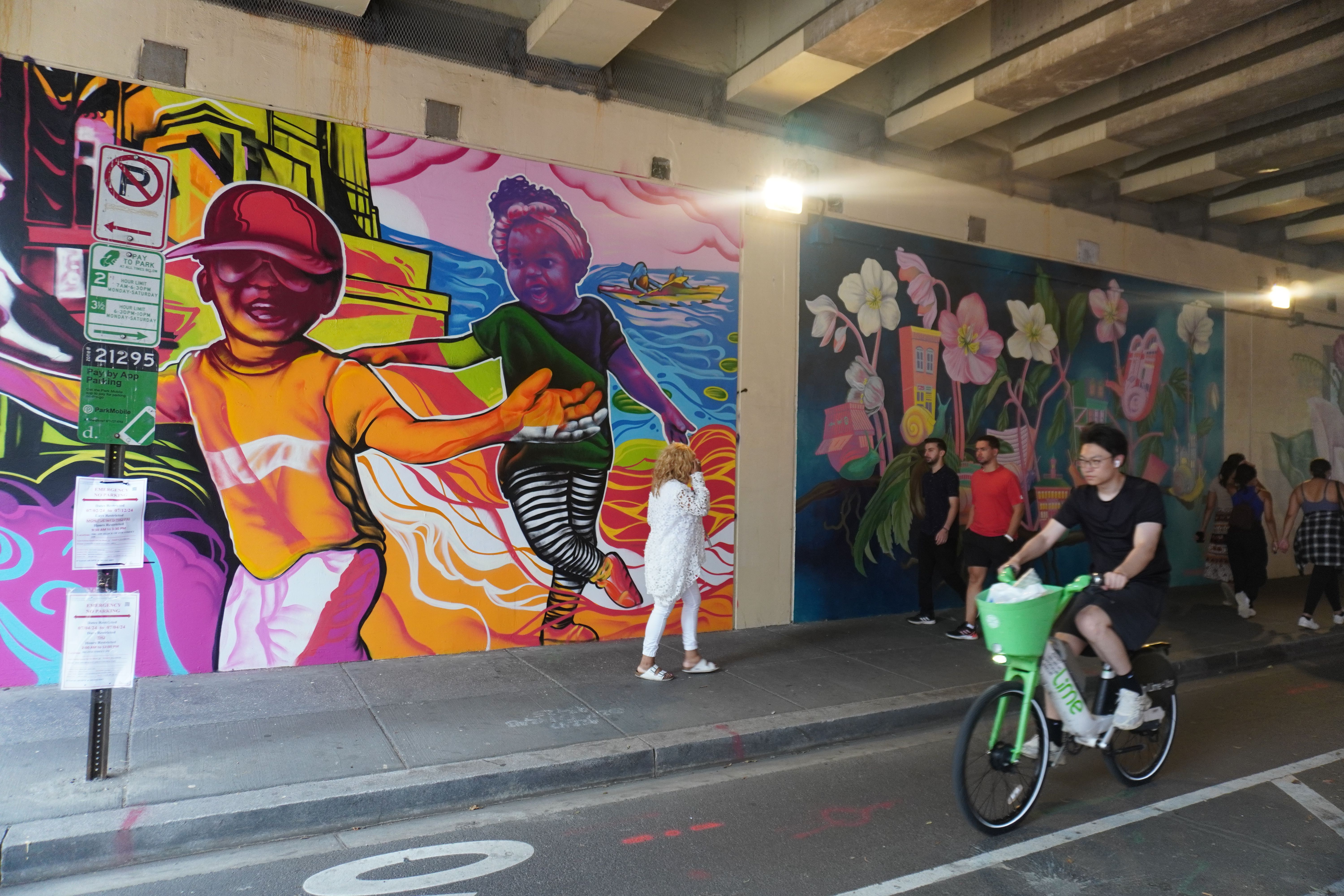 A mural under an underpass, depicting two kids playing.