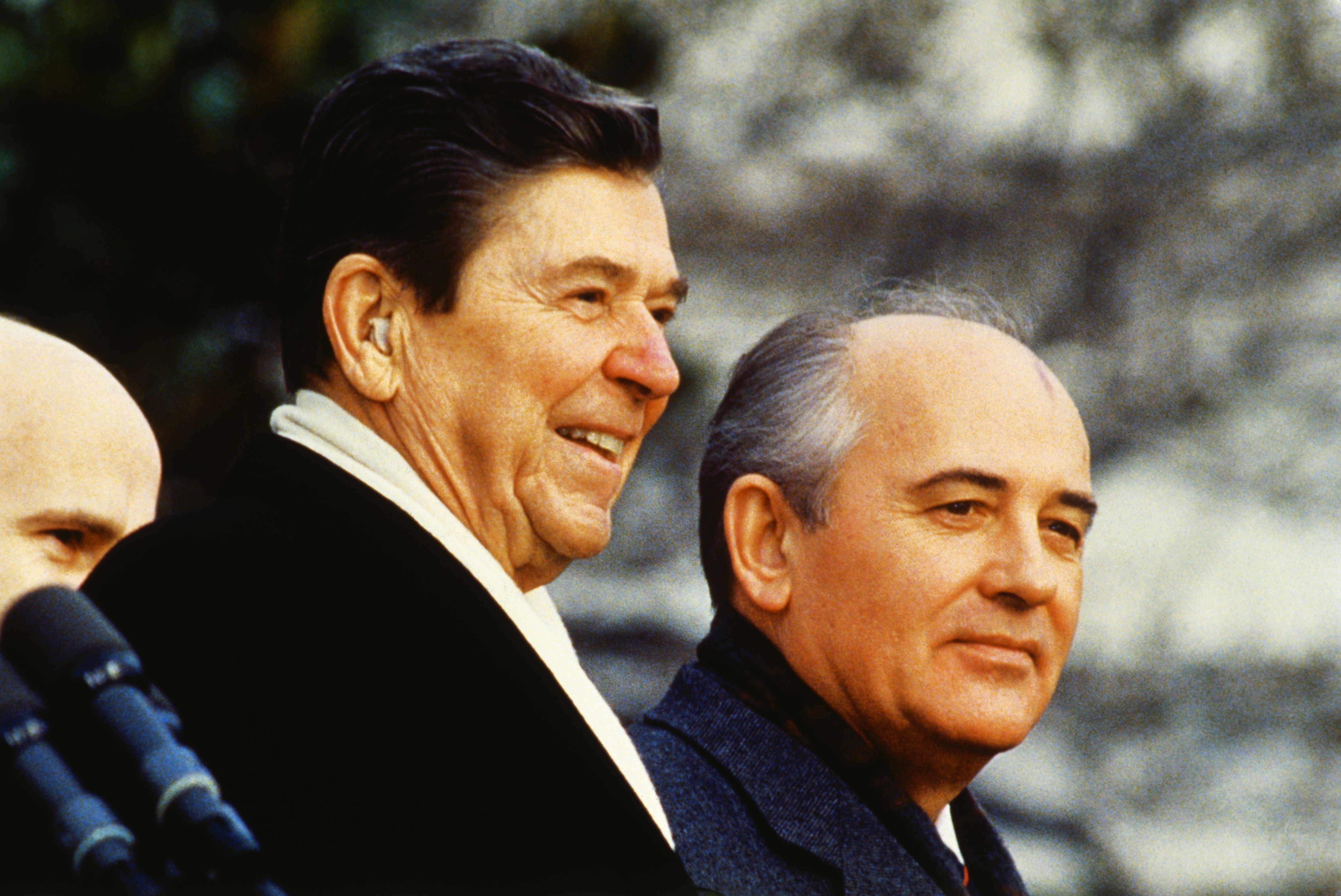 A dark, graying-haired President Reagan and a gray-haired, balding Soviet Secretary Mikhail Gorbachev smile at the welcoming ceremony at the East Lawn of the White House in 1987.