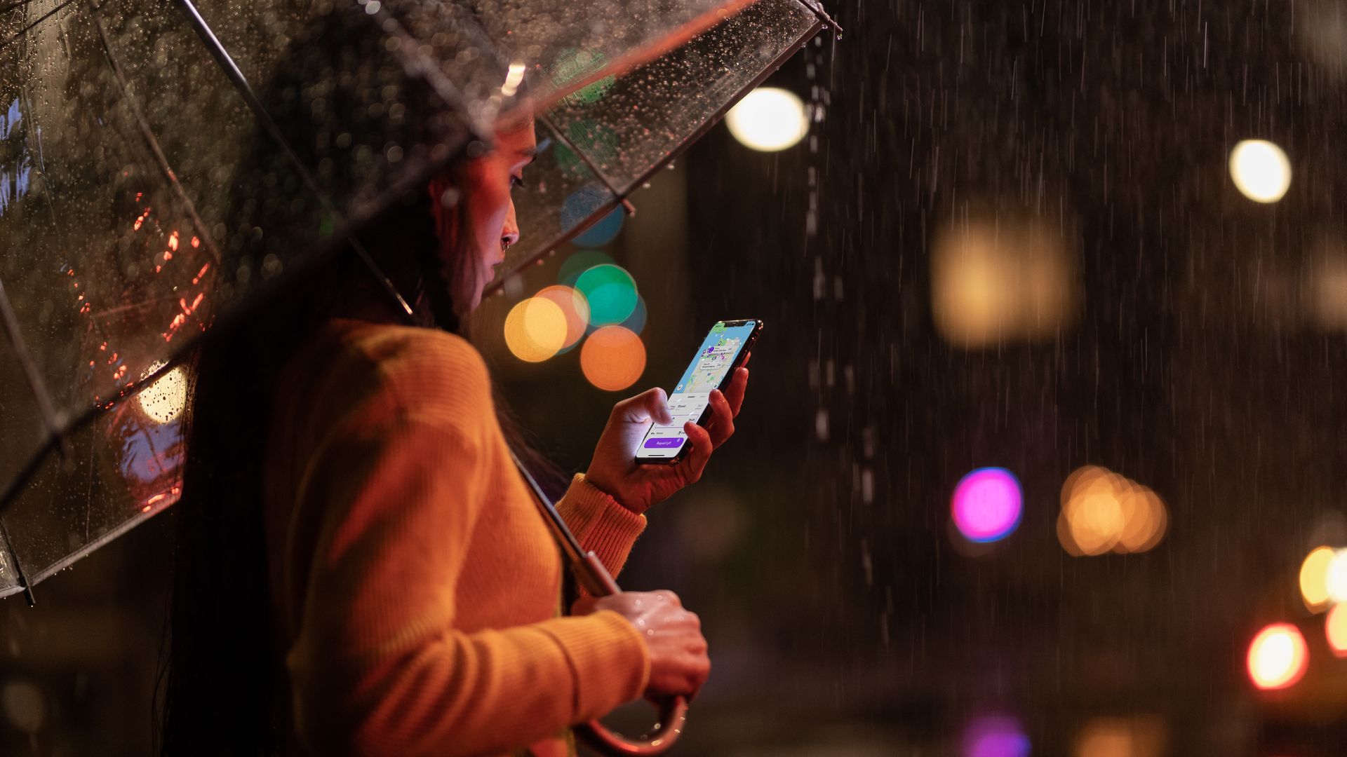 A woman holding an iPhone Xs Max in the rain