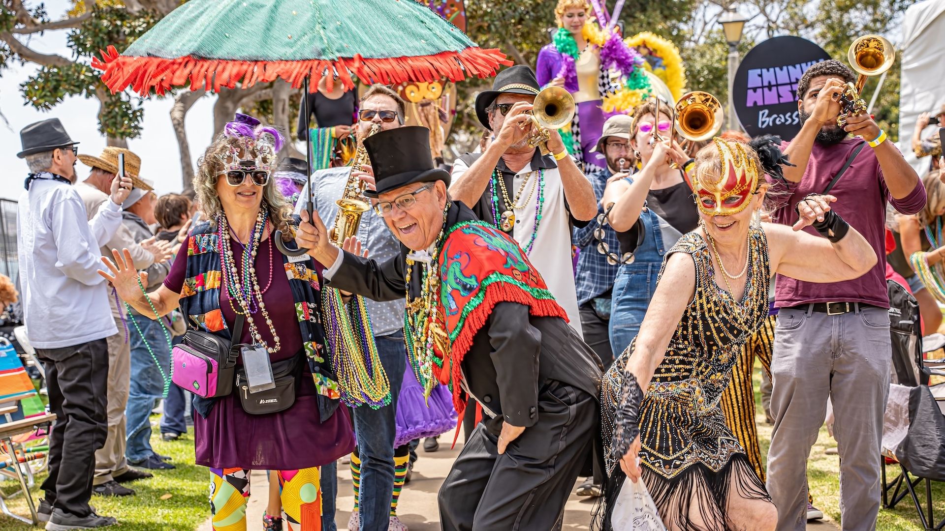 People in costumes dance and play jazz instruments in a Mardi Gras parade. 