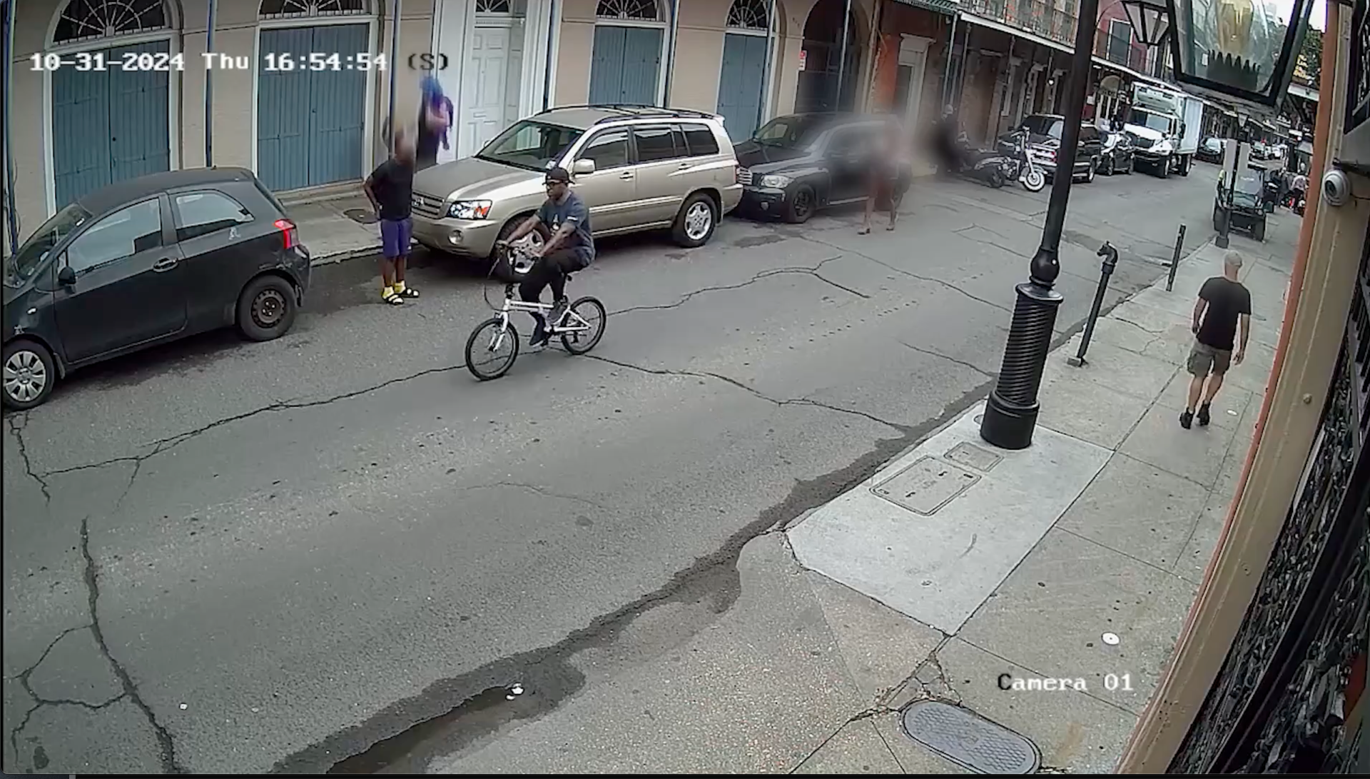 A man is seen riding a bicycle down a French Quarter street.