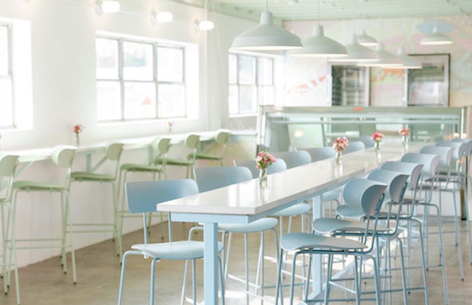 Interior of Go Fish Market shows natural lighting, high-top seating and pastel aesthetics. 