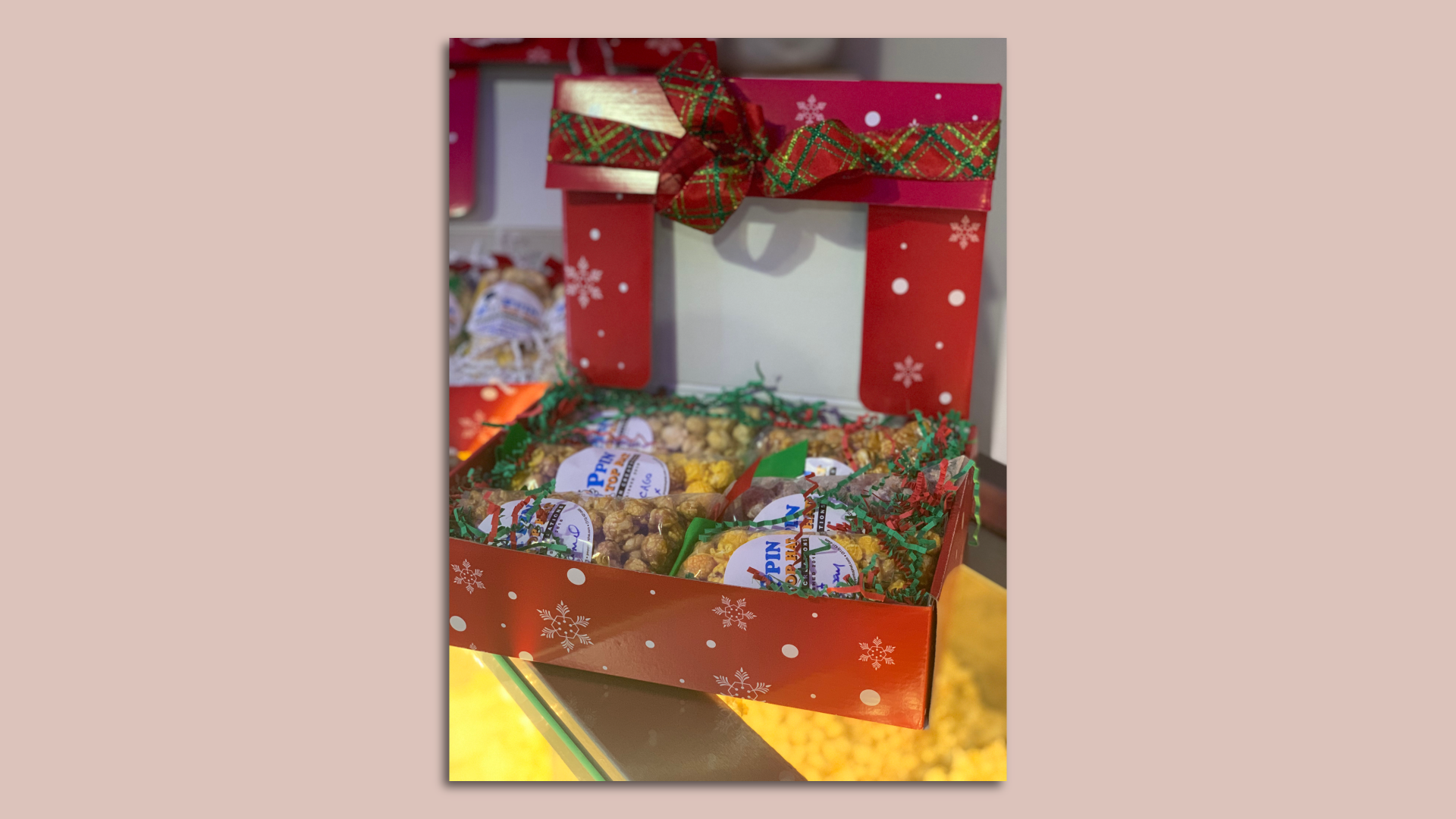 A holiday-decorated box with popcorn bags inside. 