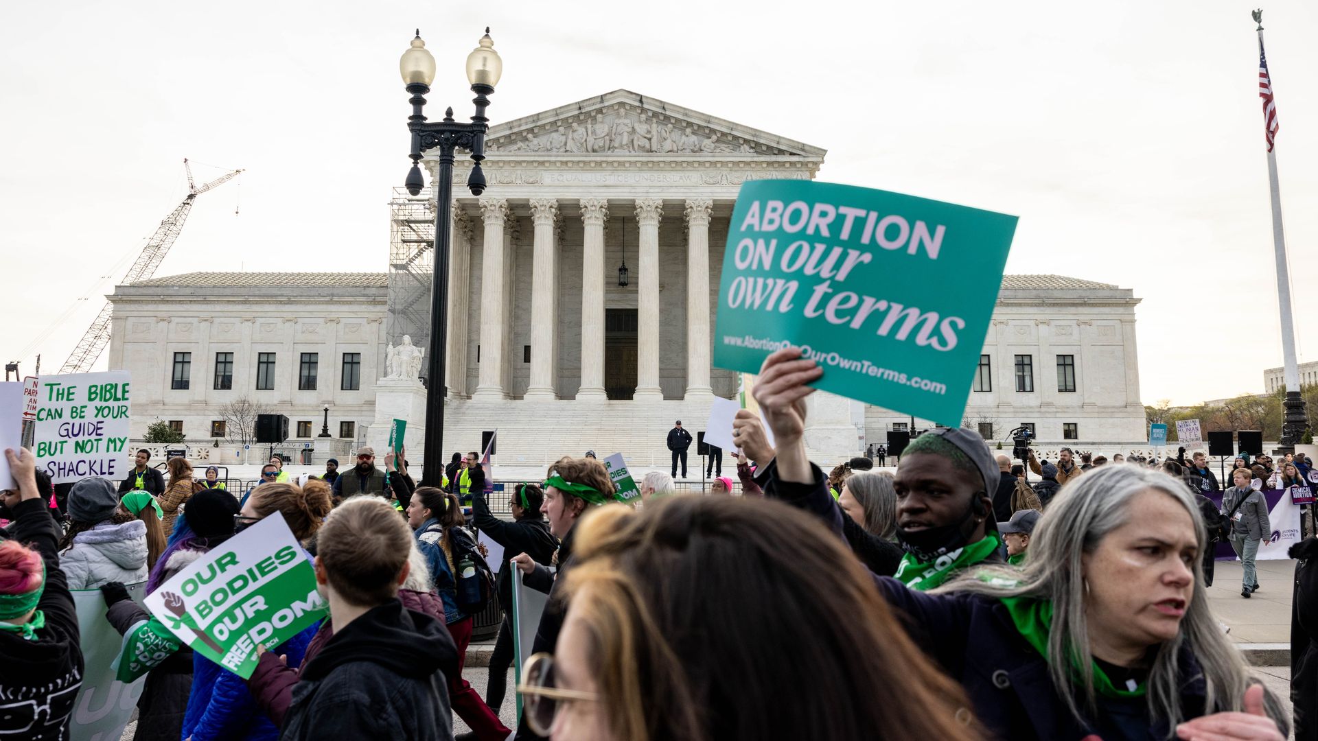 A crowd of people in the foreground with the Supreme Court in the background.
