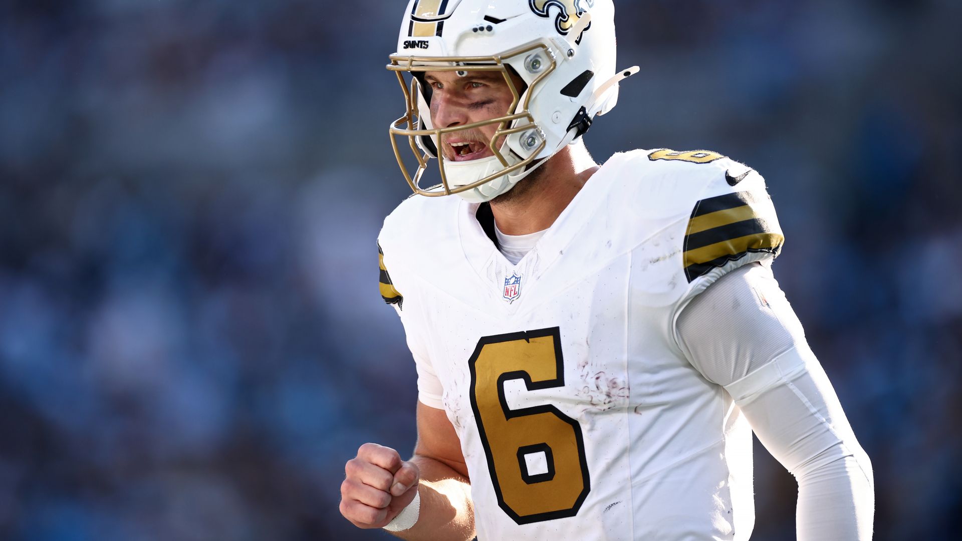 Photo shows Tyler Shough in a white Saints uniform. He's gesturing with his fist in victory after a touchdown.