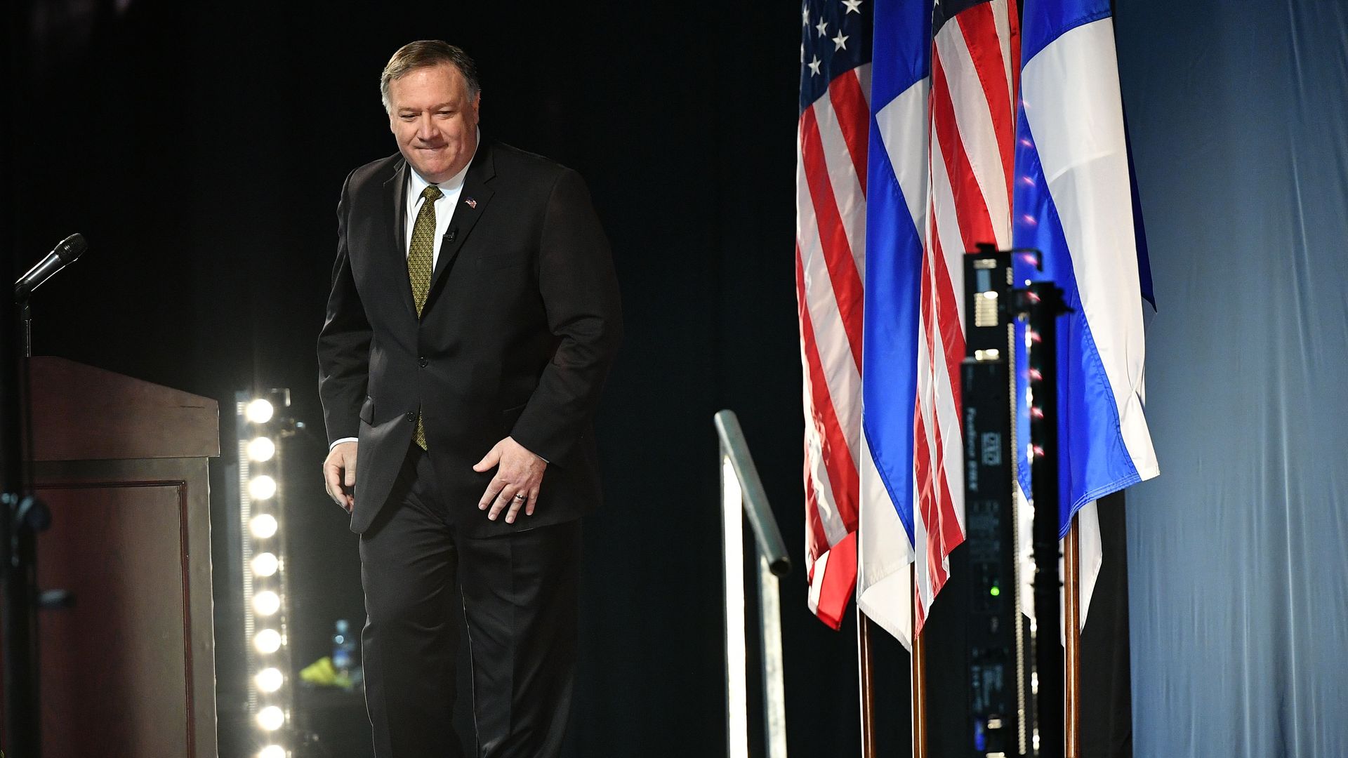In this image, Pompeo steps down from the stage at the Arctic Council. A row of American and Finland flags are next to him.