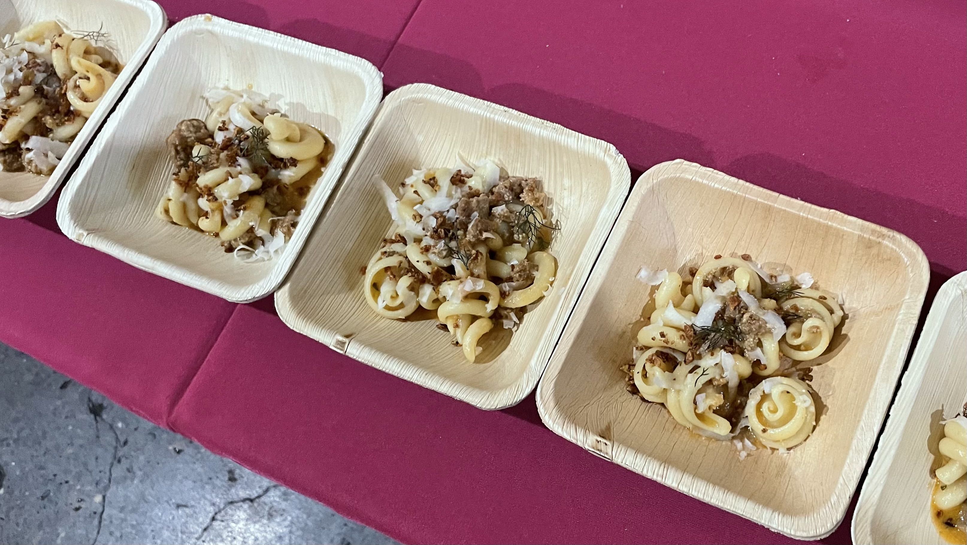 A photo of several dishes lined up in a row on a pink tablecloth.