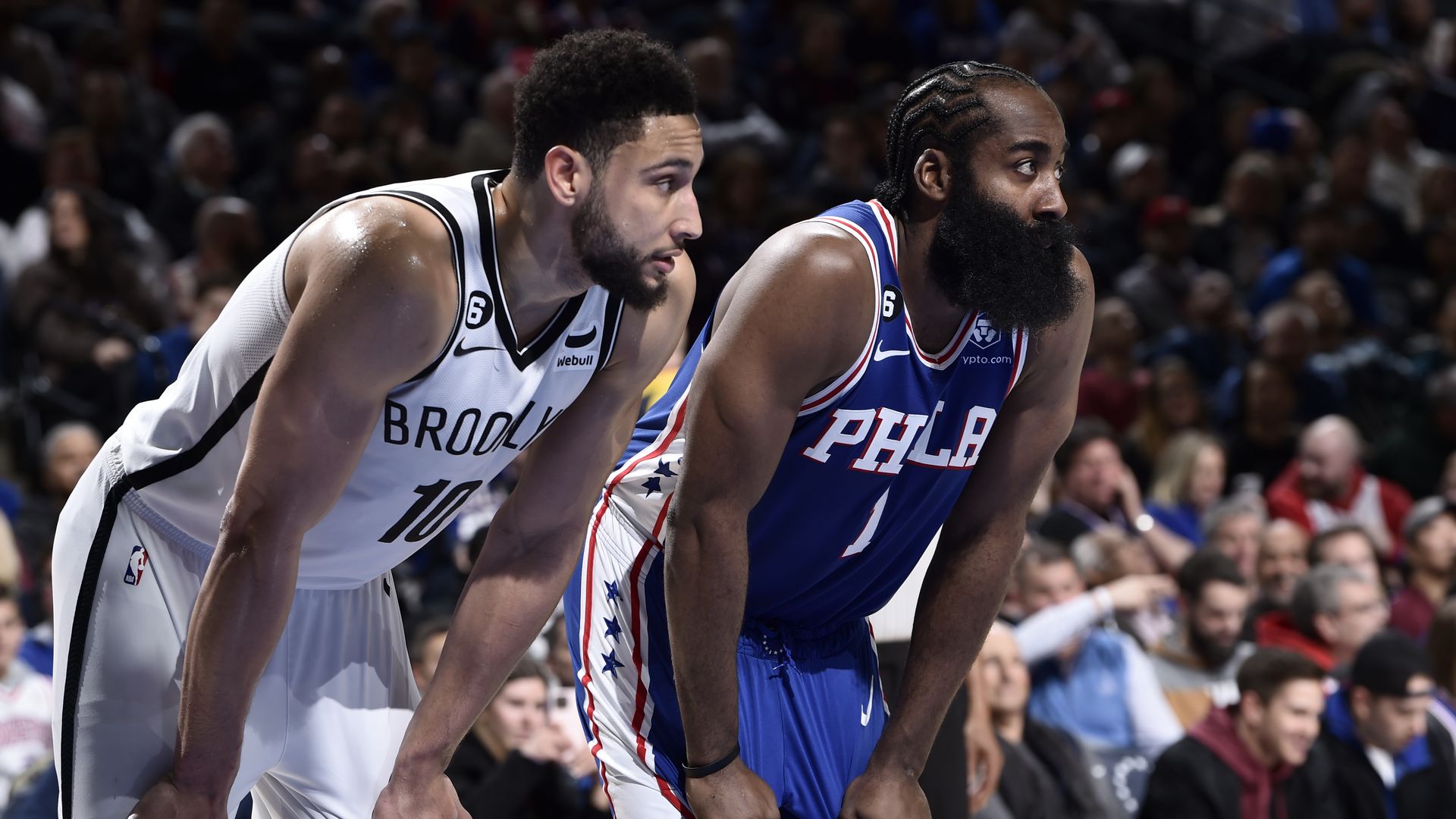 Ben Simmons (left) and James Harden watch the ball on the court while holding their hands on their knees.