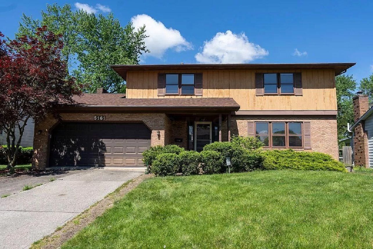 The facade of a two-story house with bushes in front. 