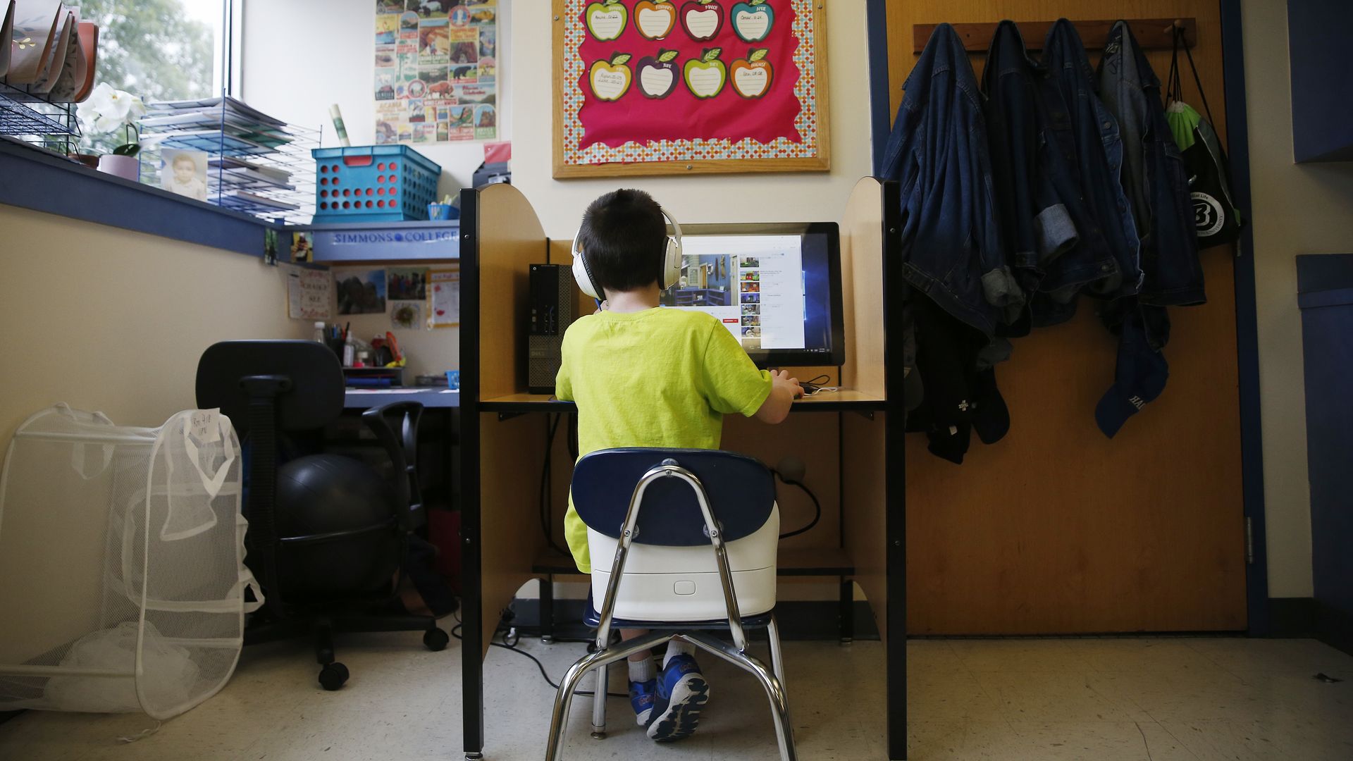 Child with headphones on watching youtube videos at a computer