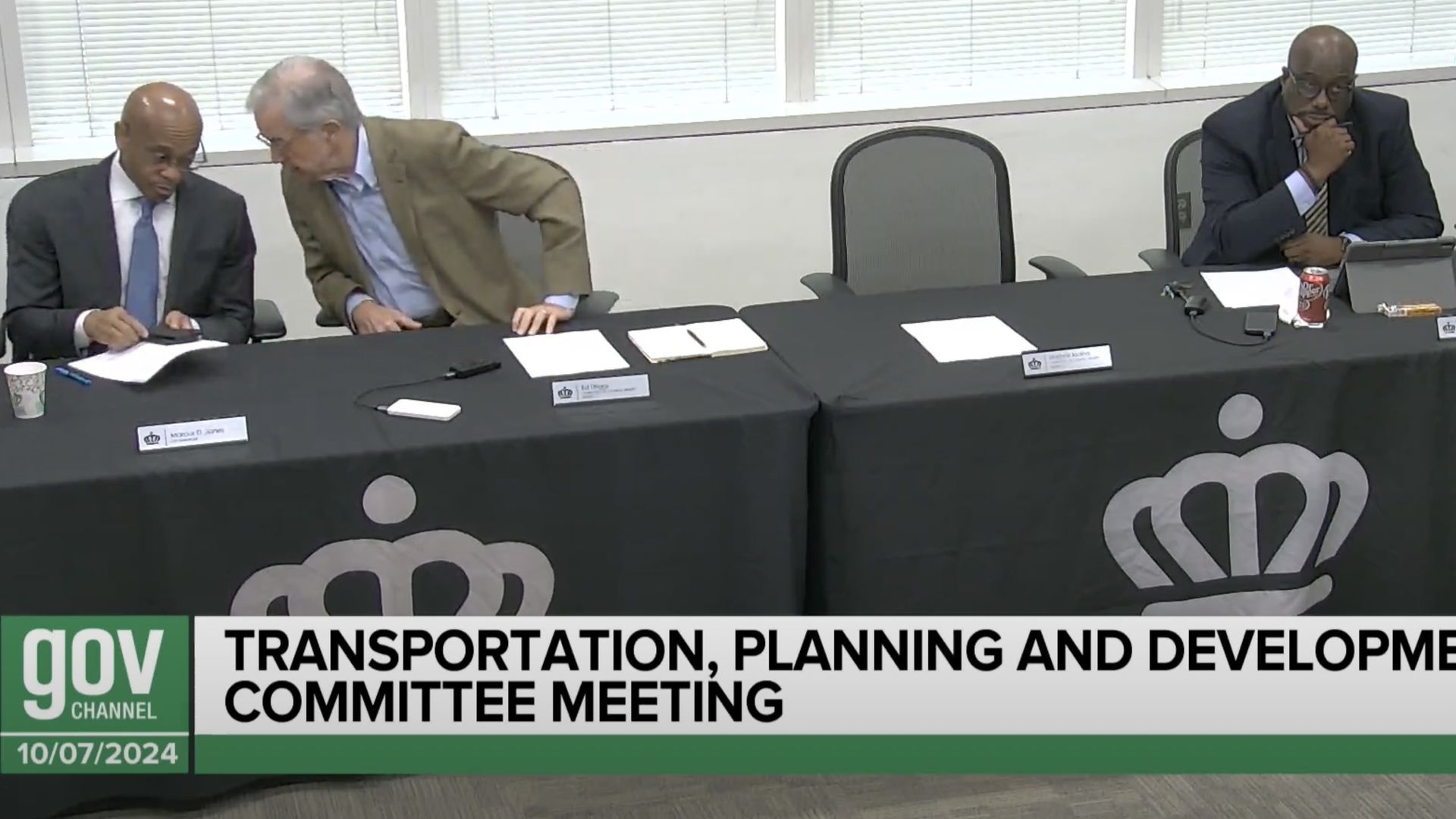 Ed Driggs leans over to speak to Marcus Jones at a table 