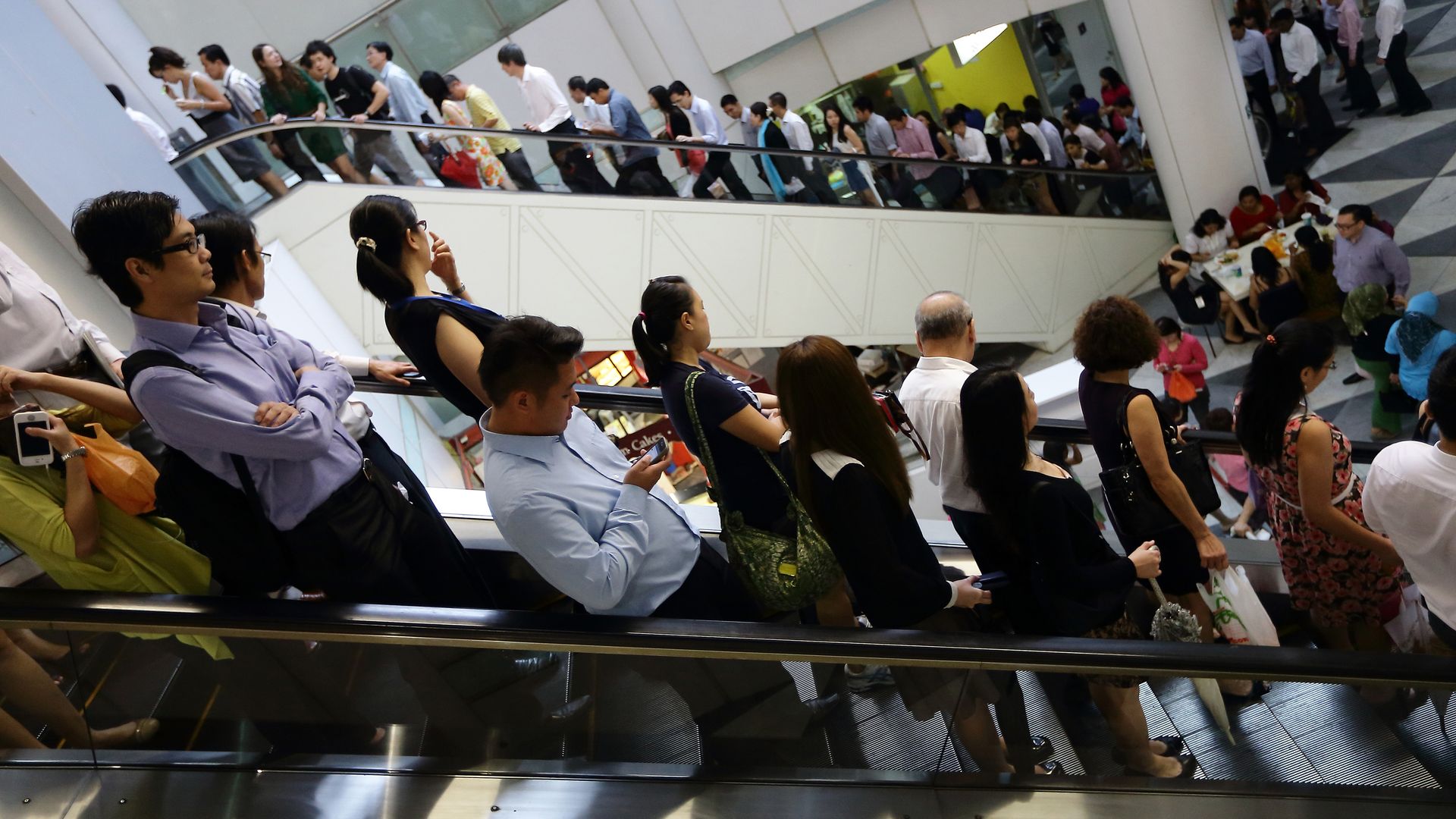 Commuters line the escalators at lunch hour at Raffles Place in Singapore