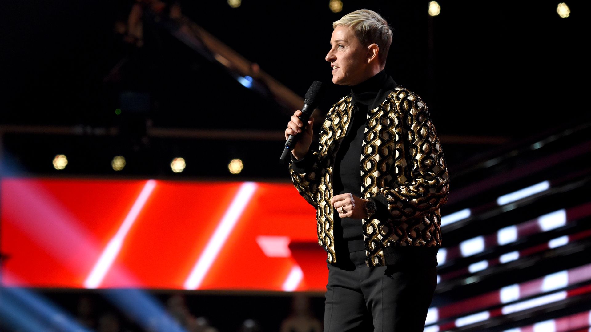  Ellen DeGeneres stands on stage and holds a microphone