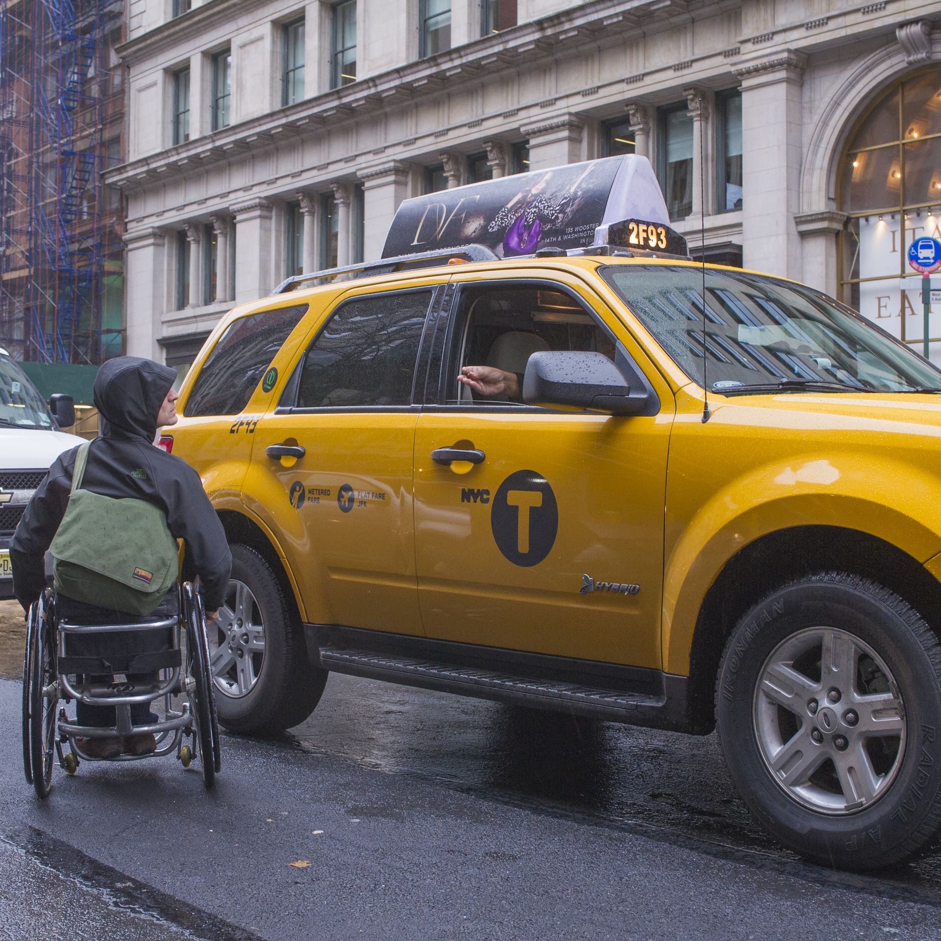 A man in a wheelchair hails a taxi