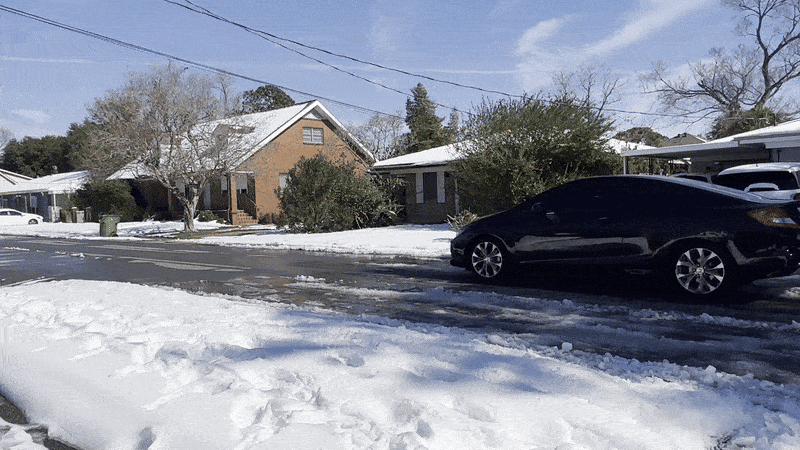 Image shows a car driving in the snow.