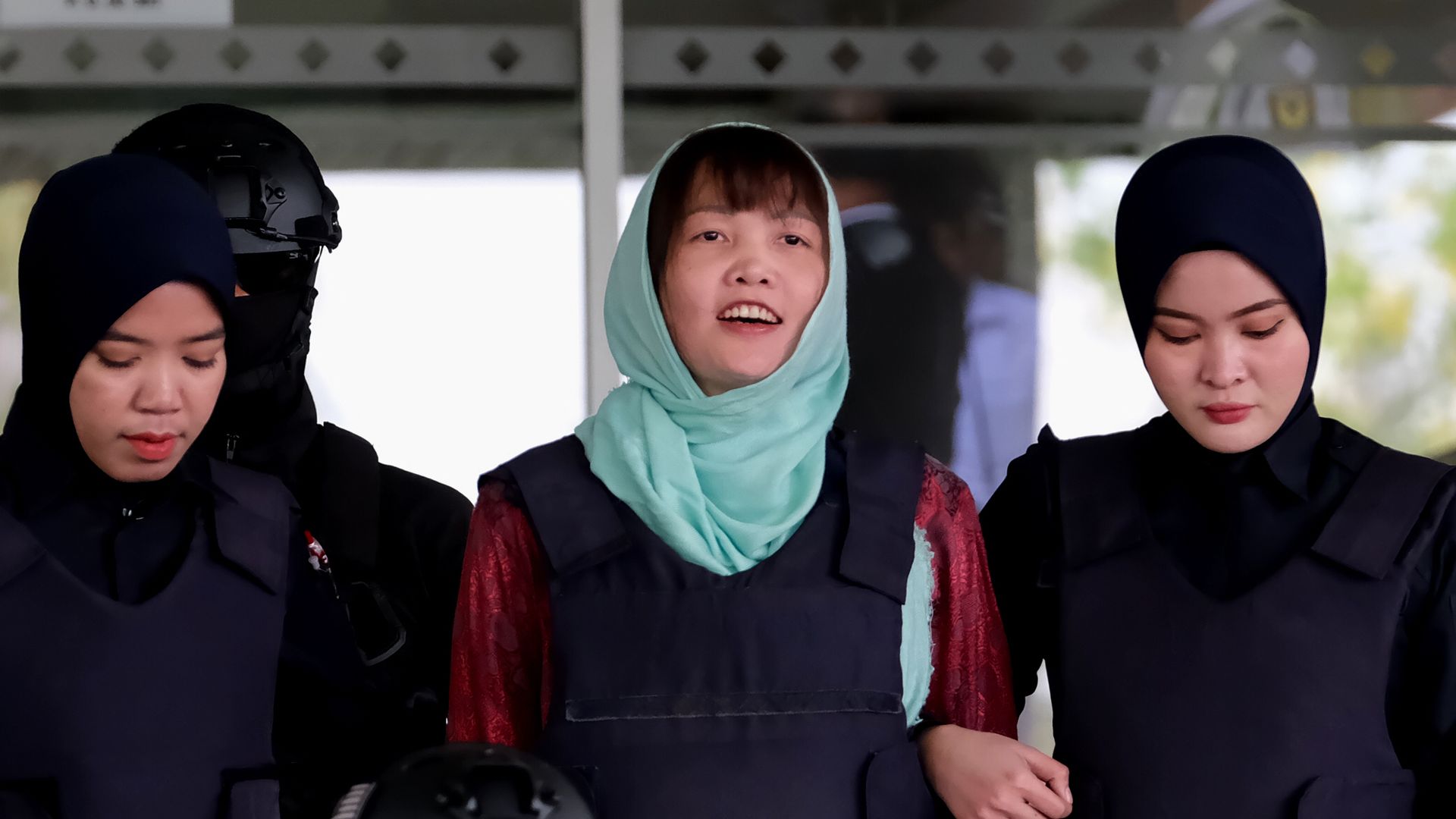 Doan Thi Huong smiles as she's escorted by police after a court session for her trial.