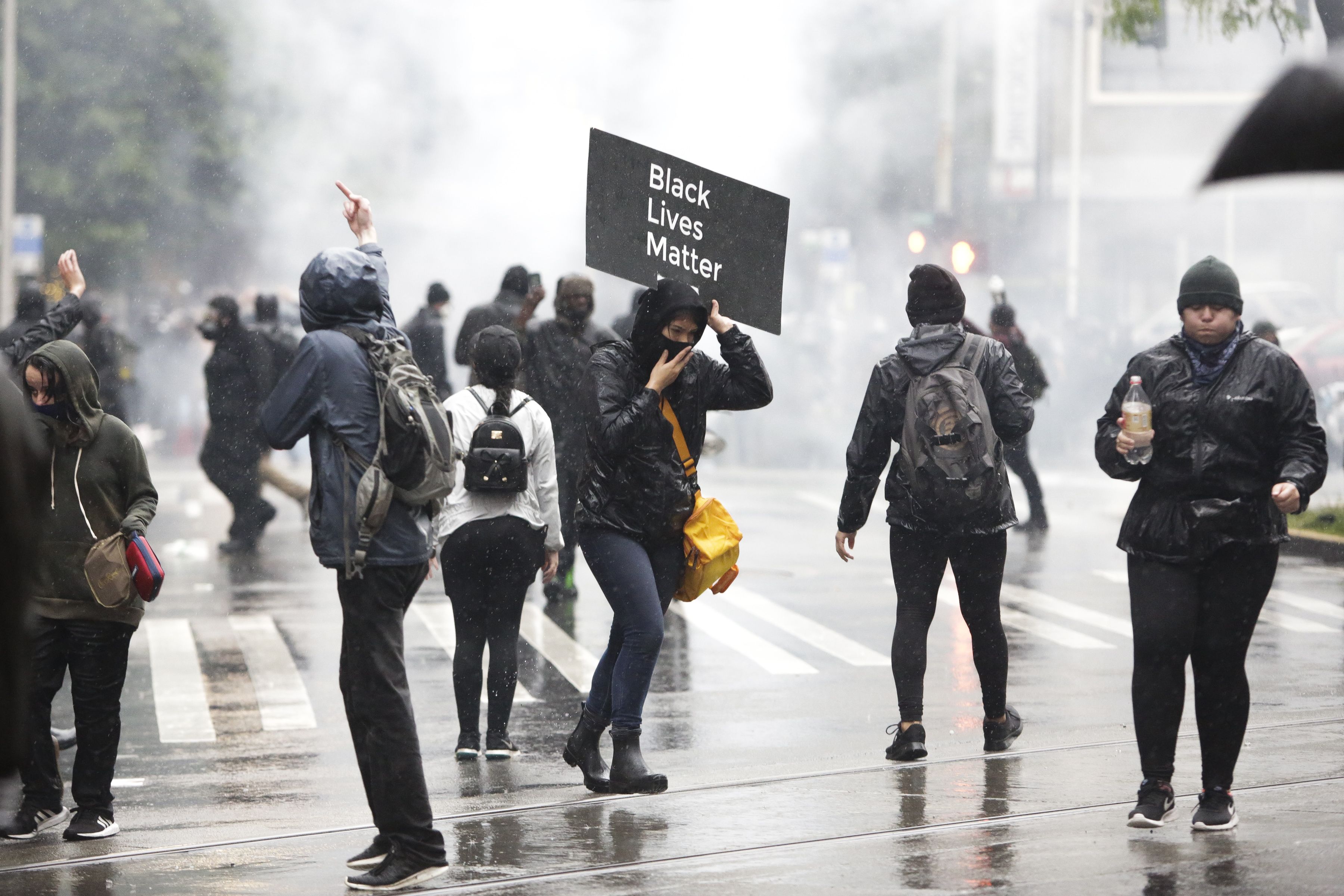 People run from tear gas after protests against the death of George Floyd, a black man who died May 25 in the custody of Minneapolis Police, turned destructive in Seattle
