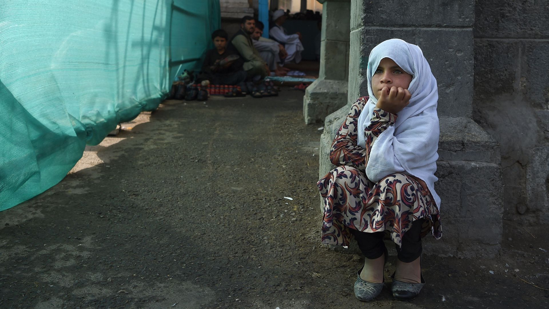 An Afghan girl looks on as she begs for alms.