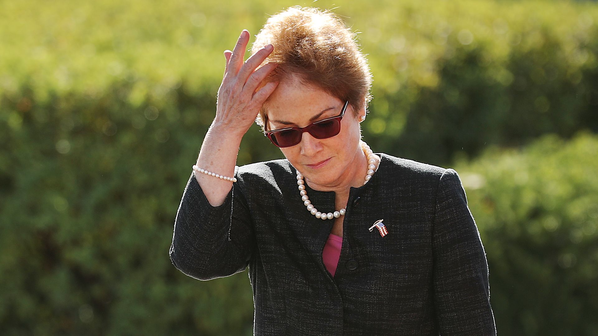 In this image, the ambassador walks and fixes her hair