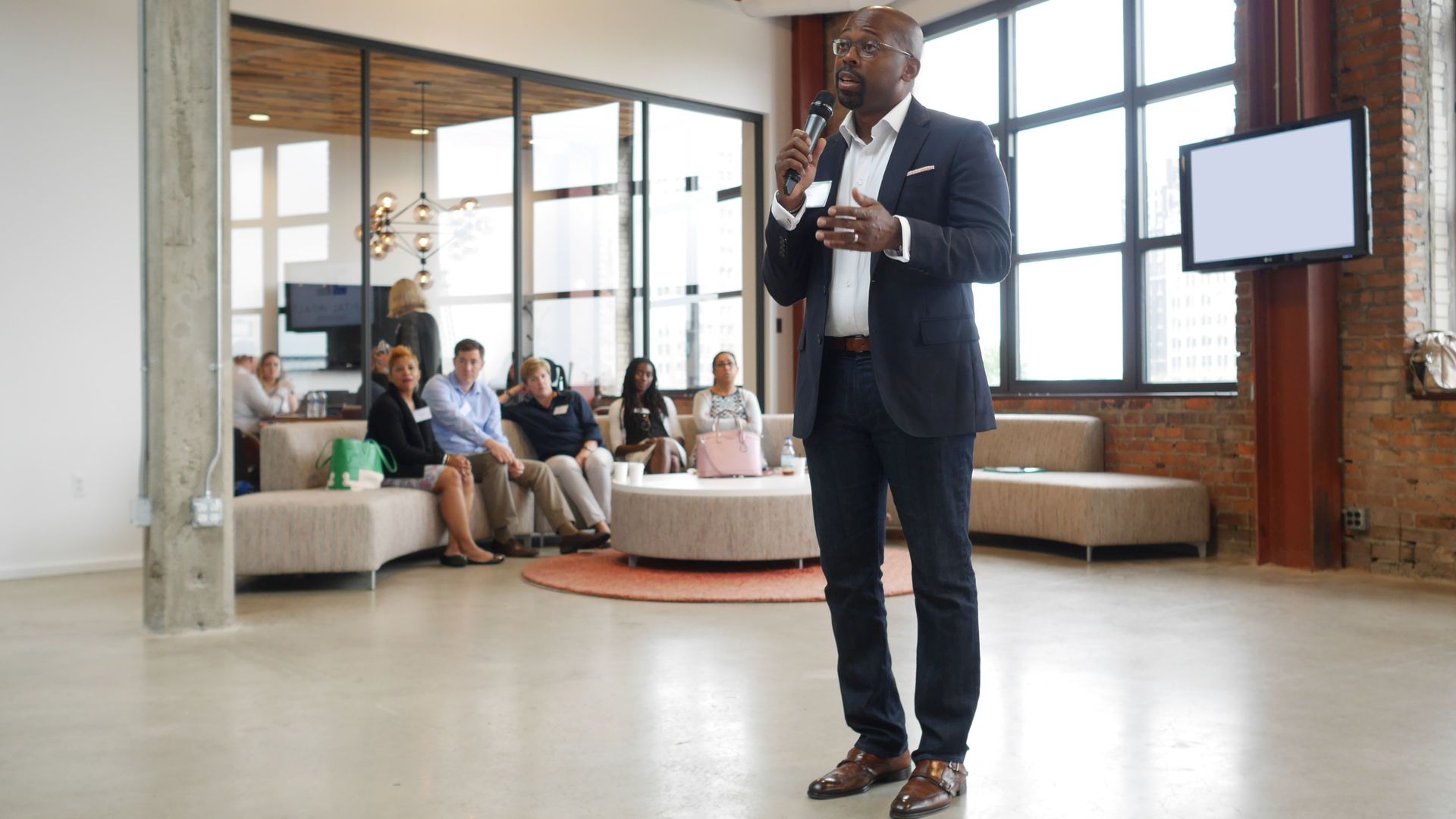 A man with a microphone talks to a room of people
