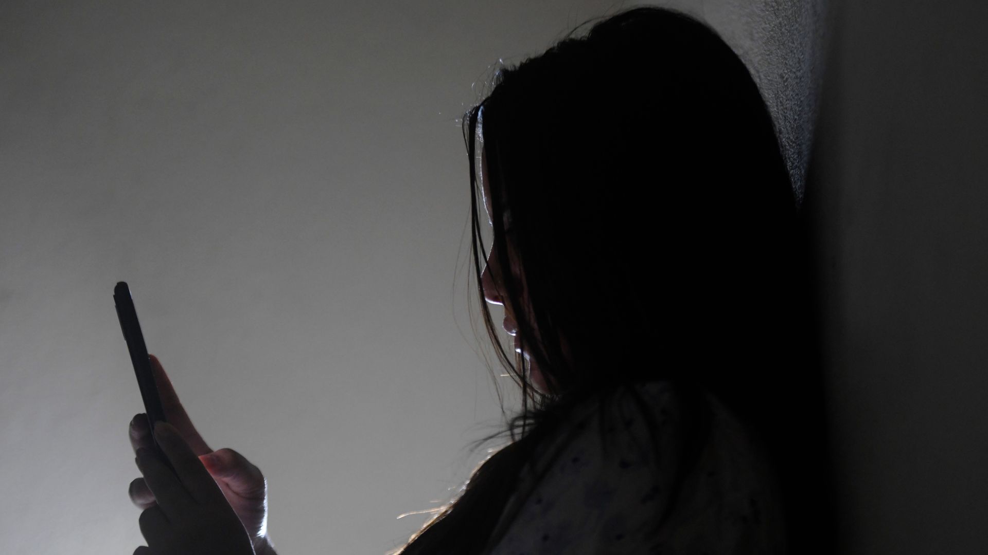 Woman in silhouette looking at her phone.