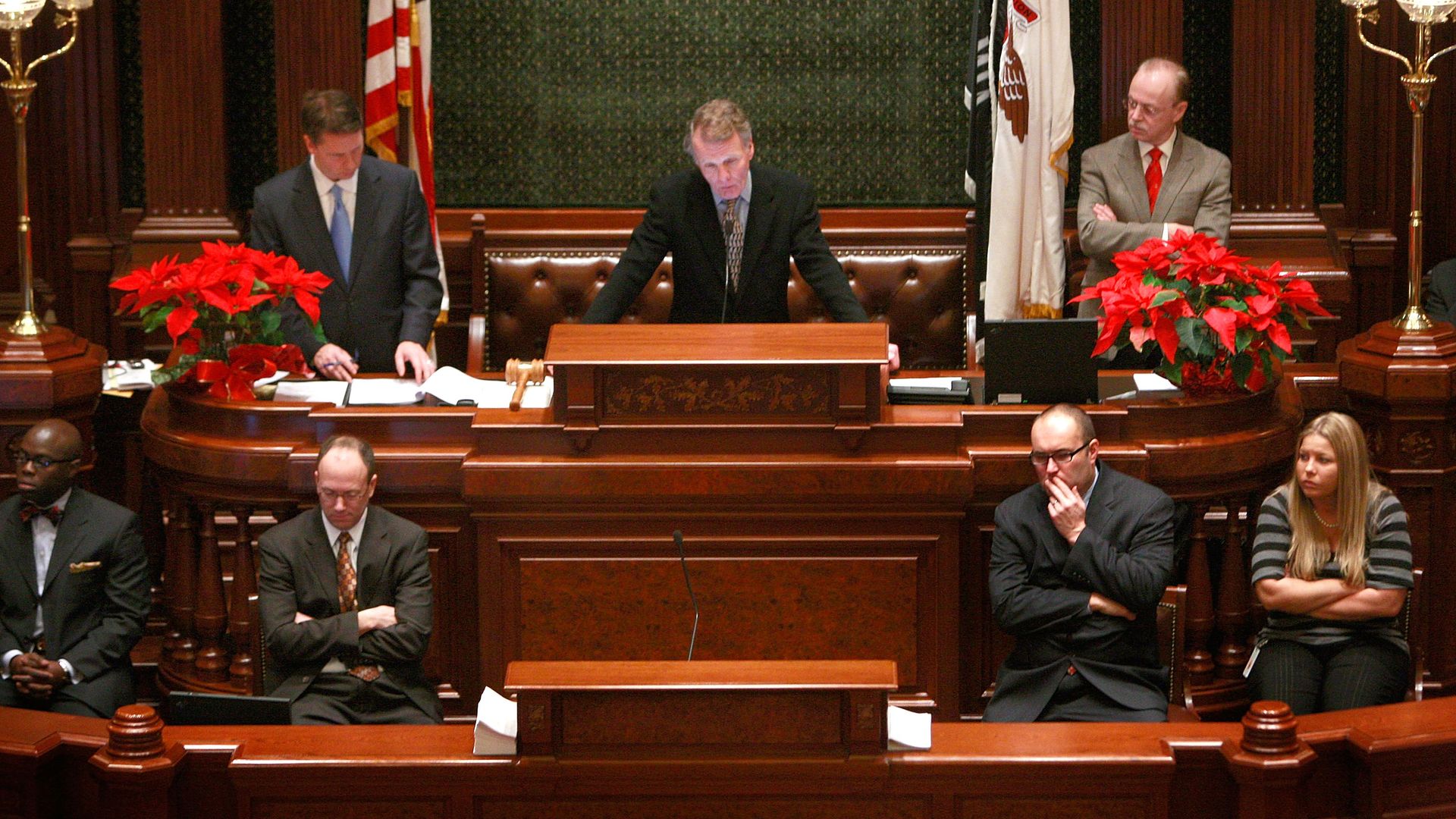 Photo of a man standing behind a podium during a legislative session in a chamber 