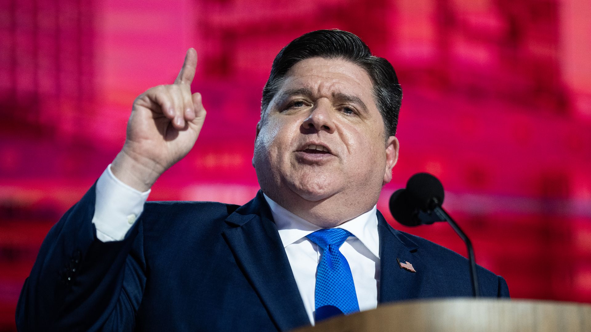Photo of a man pointing while talking at a podium 