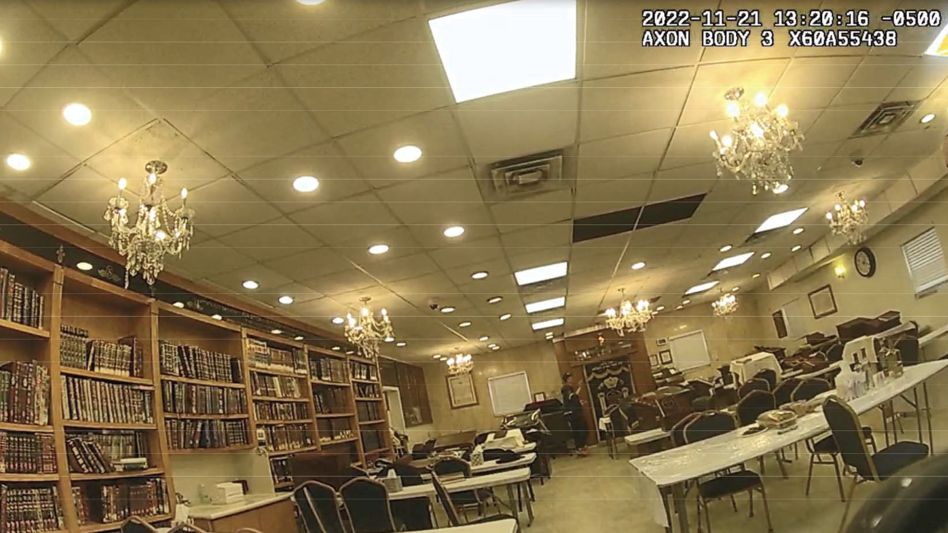 Bodycam footage shows a room with tables, chairs and bookshelves 