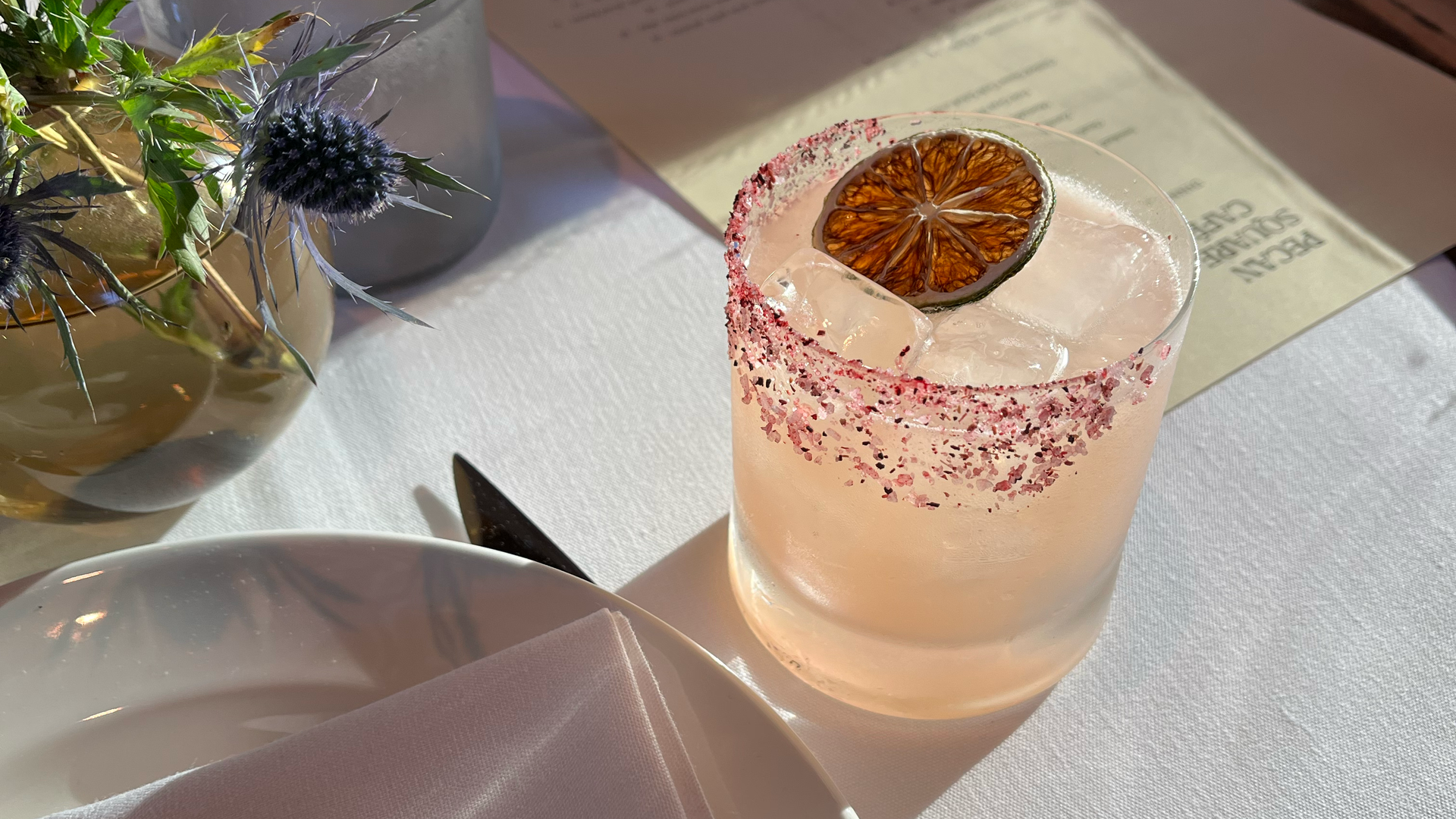 A mezcal margarita sits in the sunlight on a table
