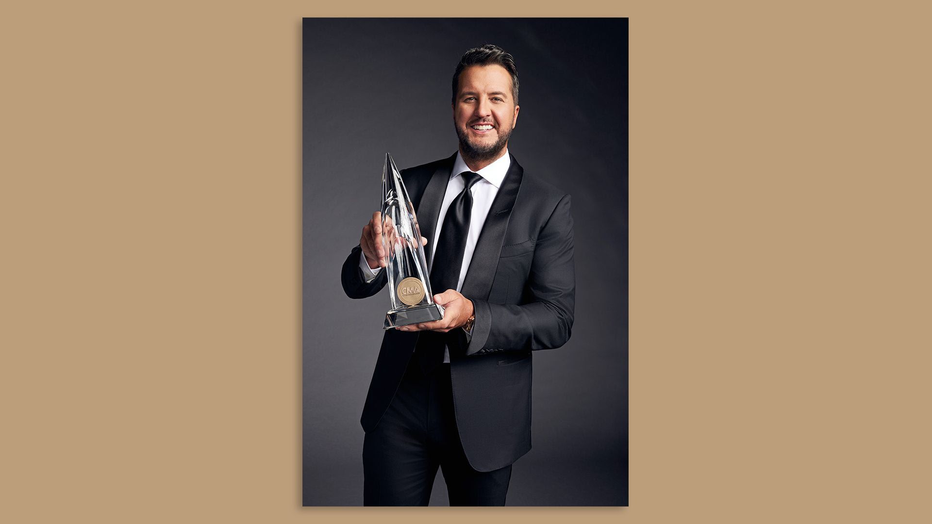 Luke Bryan holding a CMA award, which he hosts tonight