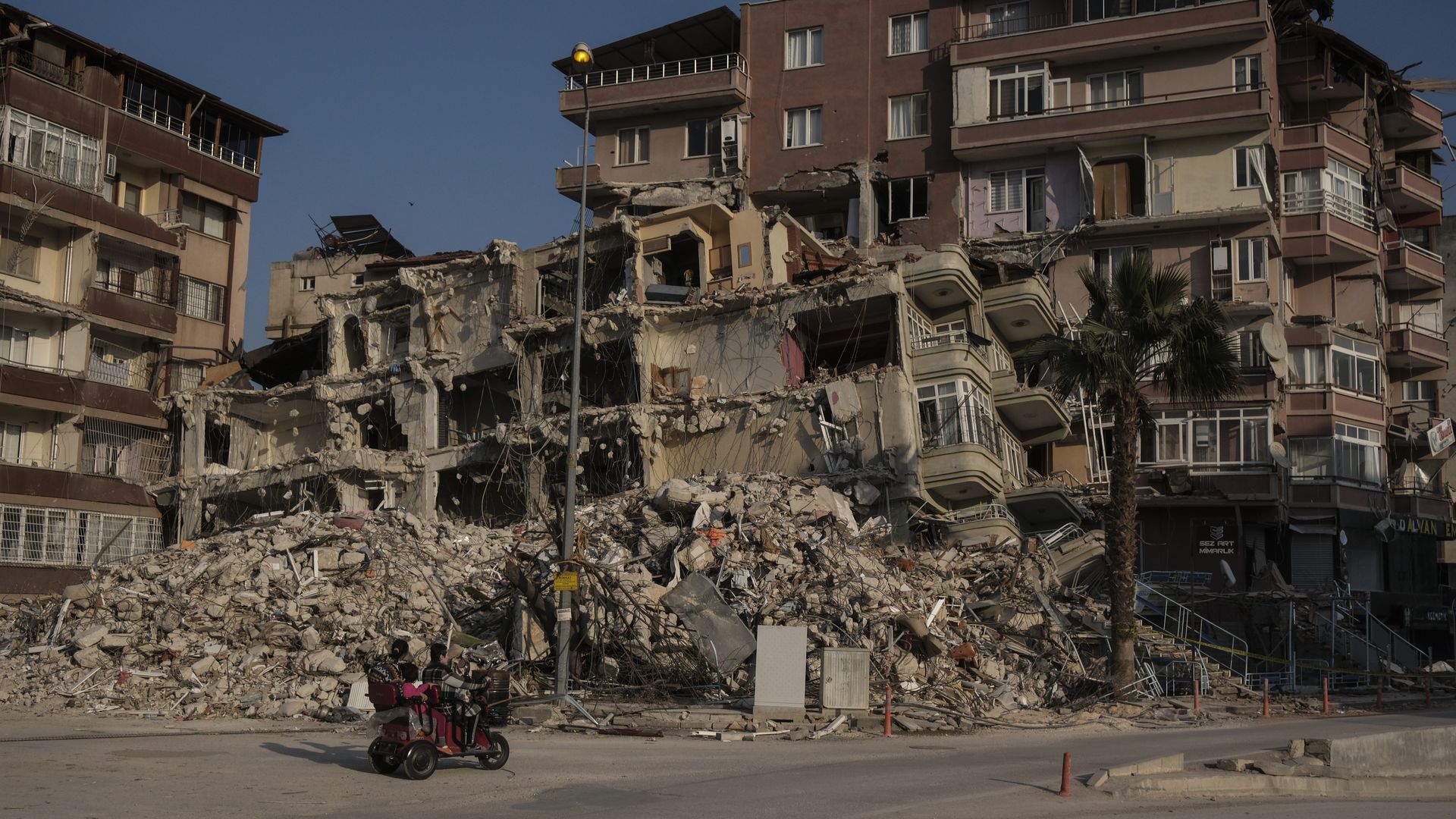 An earthquake survivor family pass by a ruined building