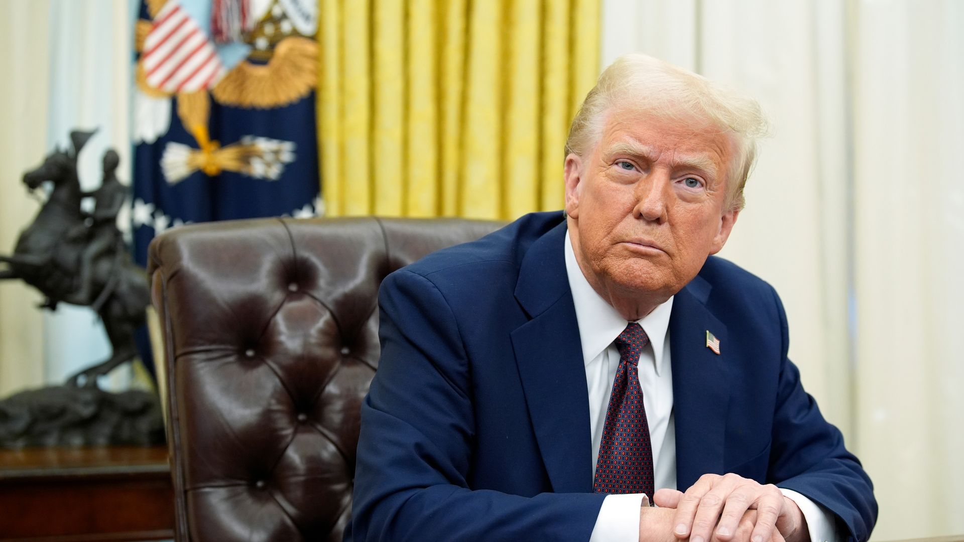 President Trump sits at the resolute desk in the Oval Office.