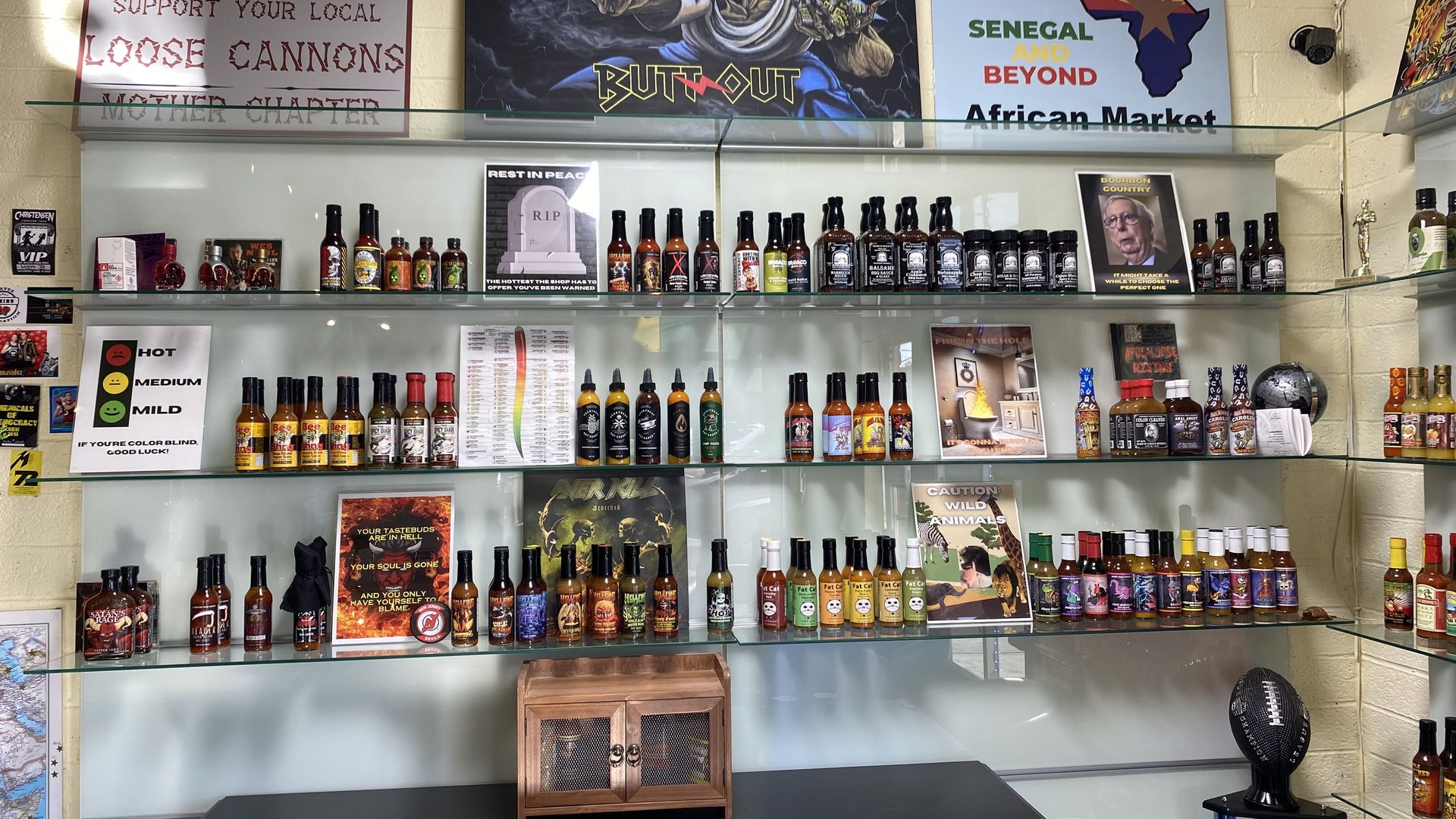Three shelves filled with bottles of hot sauce. 