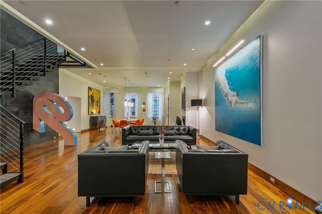 A big living room with huge leather couches and a massive blue painting