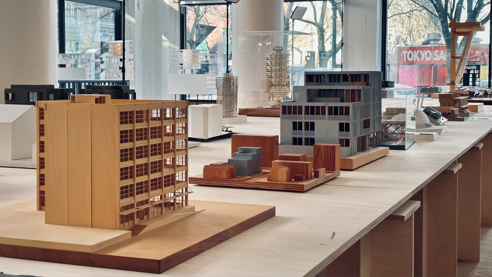 A photo of several mini architectural models of buildings lined up on a table.