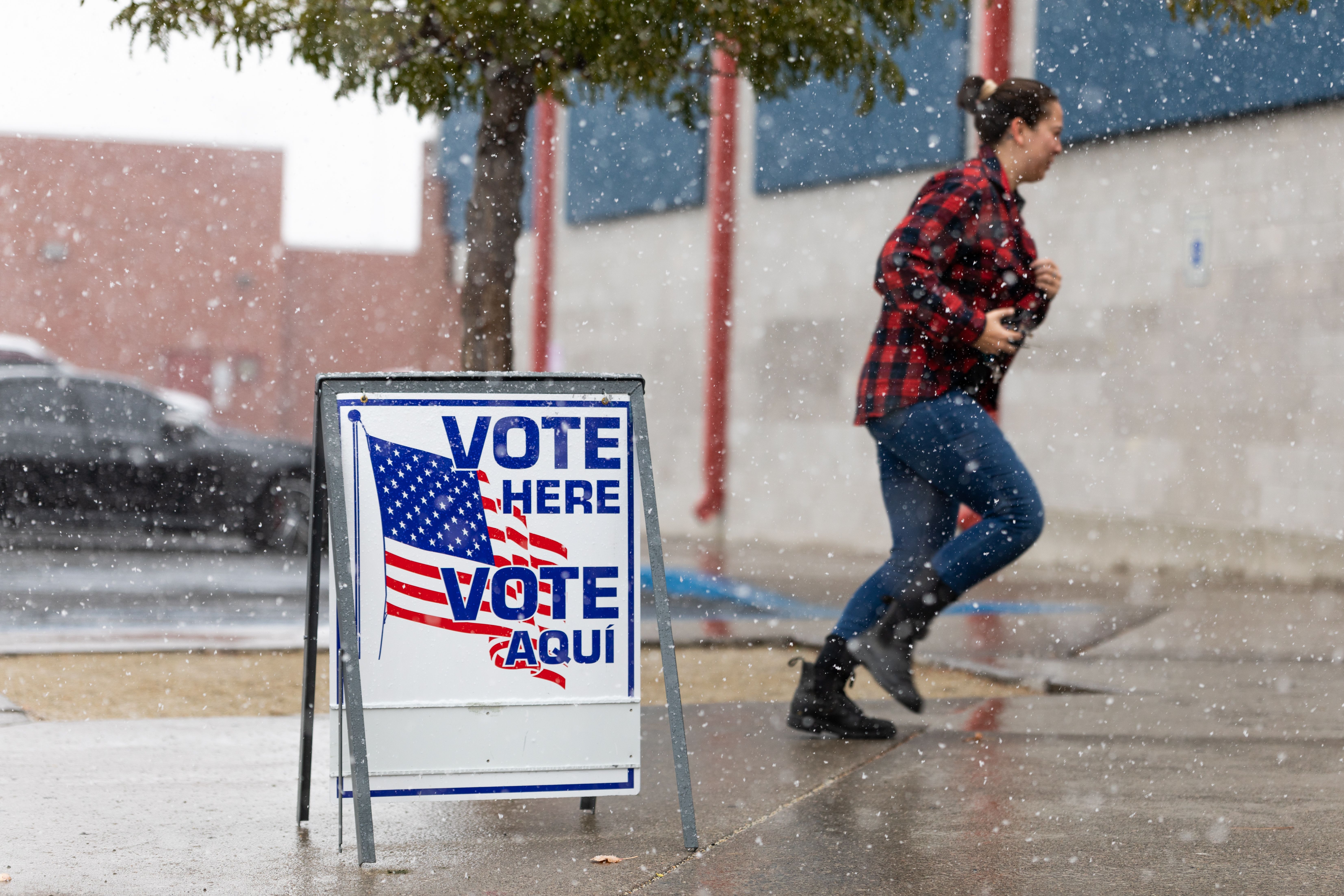 A Washoe County voter runs through the snow to cast their ballot inside Reno High School on November 8, 2022 in Reno, Nevada.