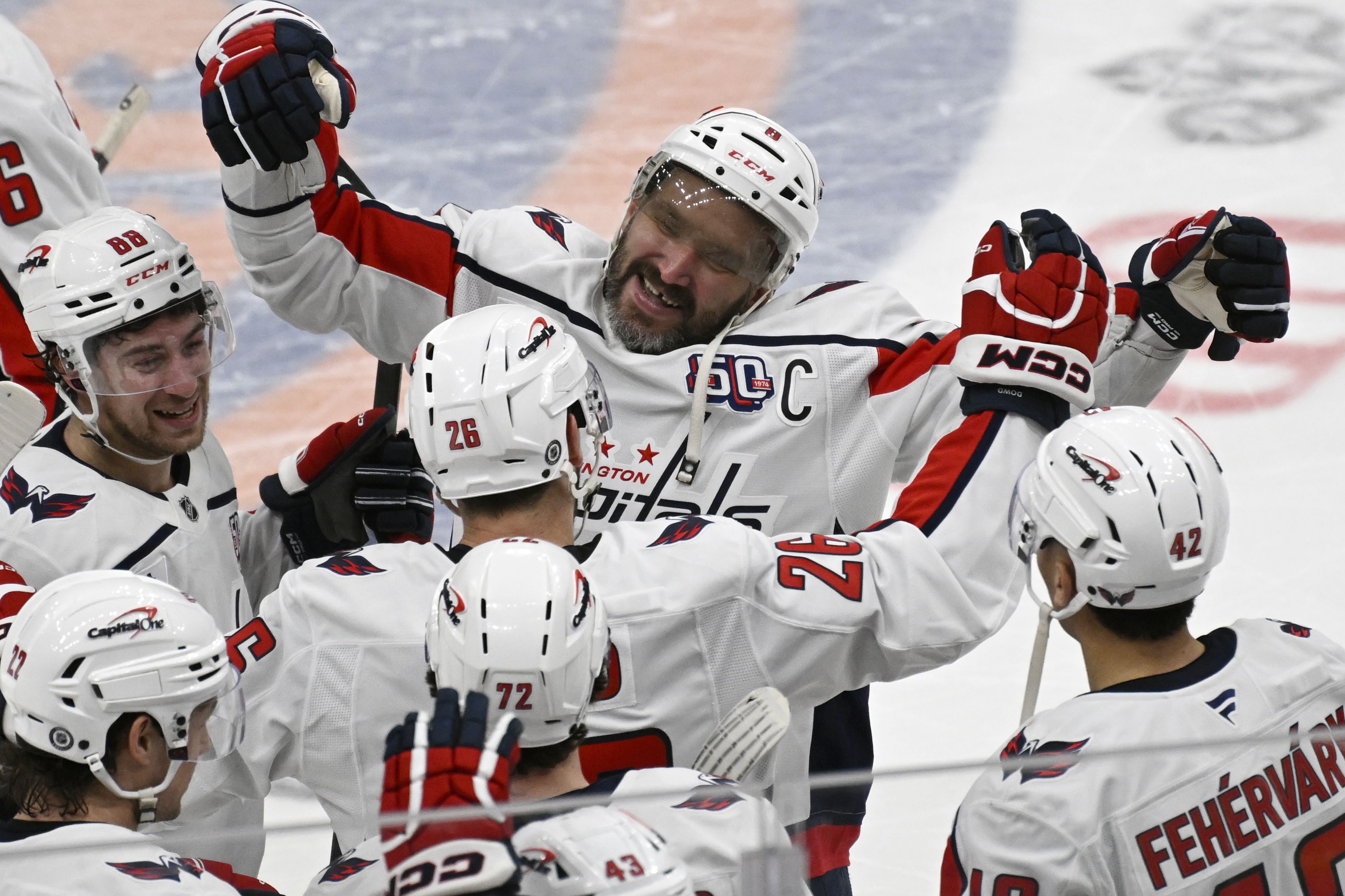 Teammates mob Washington Capitals left wing Alex Ovechkin (8) after he breaks the NHL scoring record with 895 goals during the second period of an NHL hockey game against the New York Islanders at UBS Arena in Queens, NY on April 6, 2025. (Photo by John McDonnell/For The Washington Post via Getty Im
