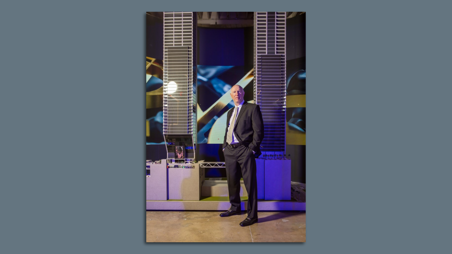 man in suit beside model of condos