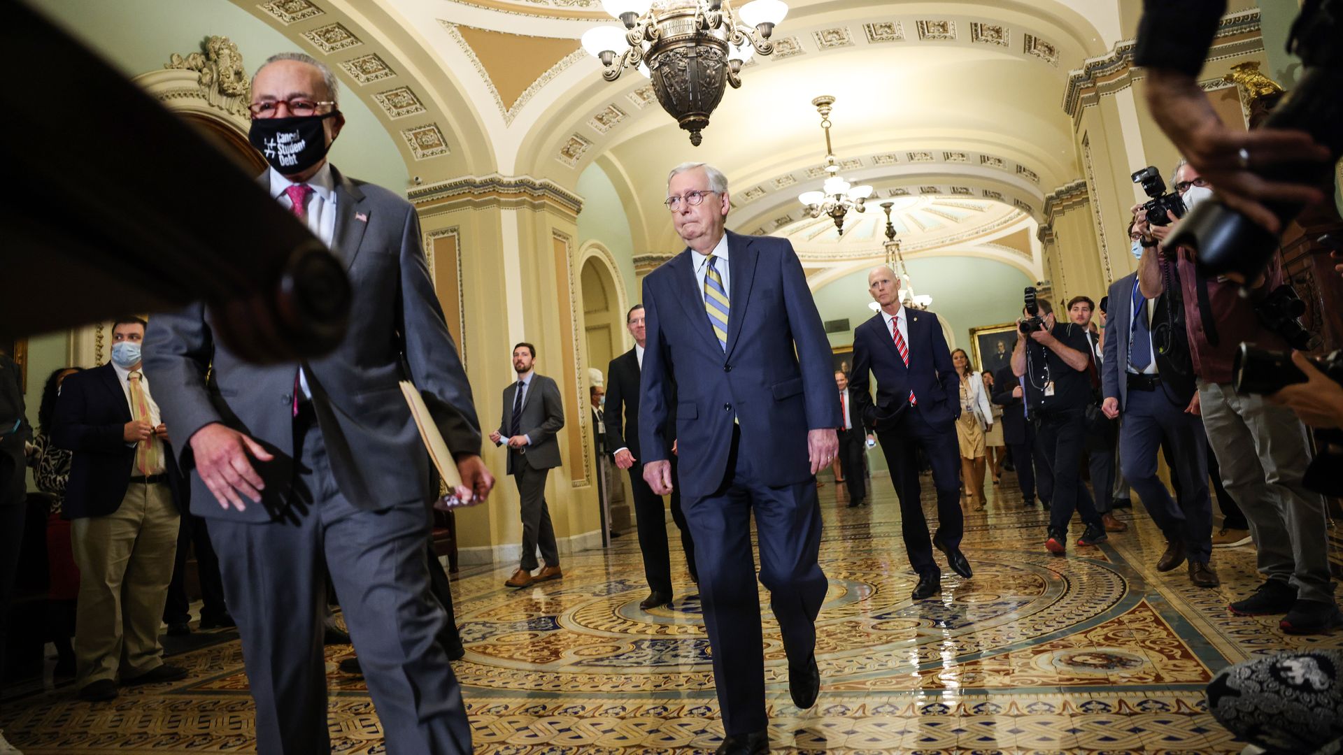 Senate Minority Leader Chuck Schumer is seen cutting off Senate Minority Leader Mitch McConnell as they head for the same lectern.