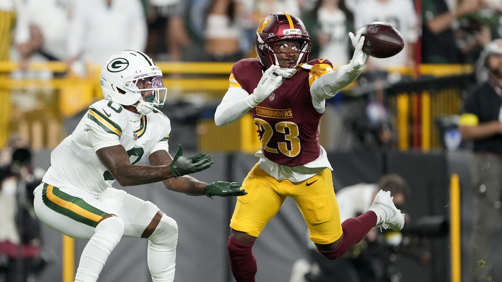 A Washington cornerback bats away a pass in front of a Green Bay receiver.