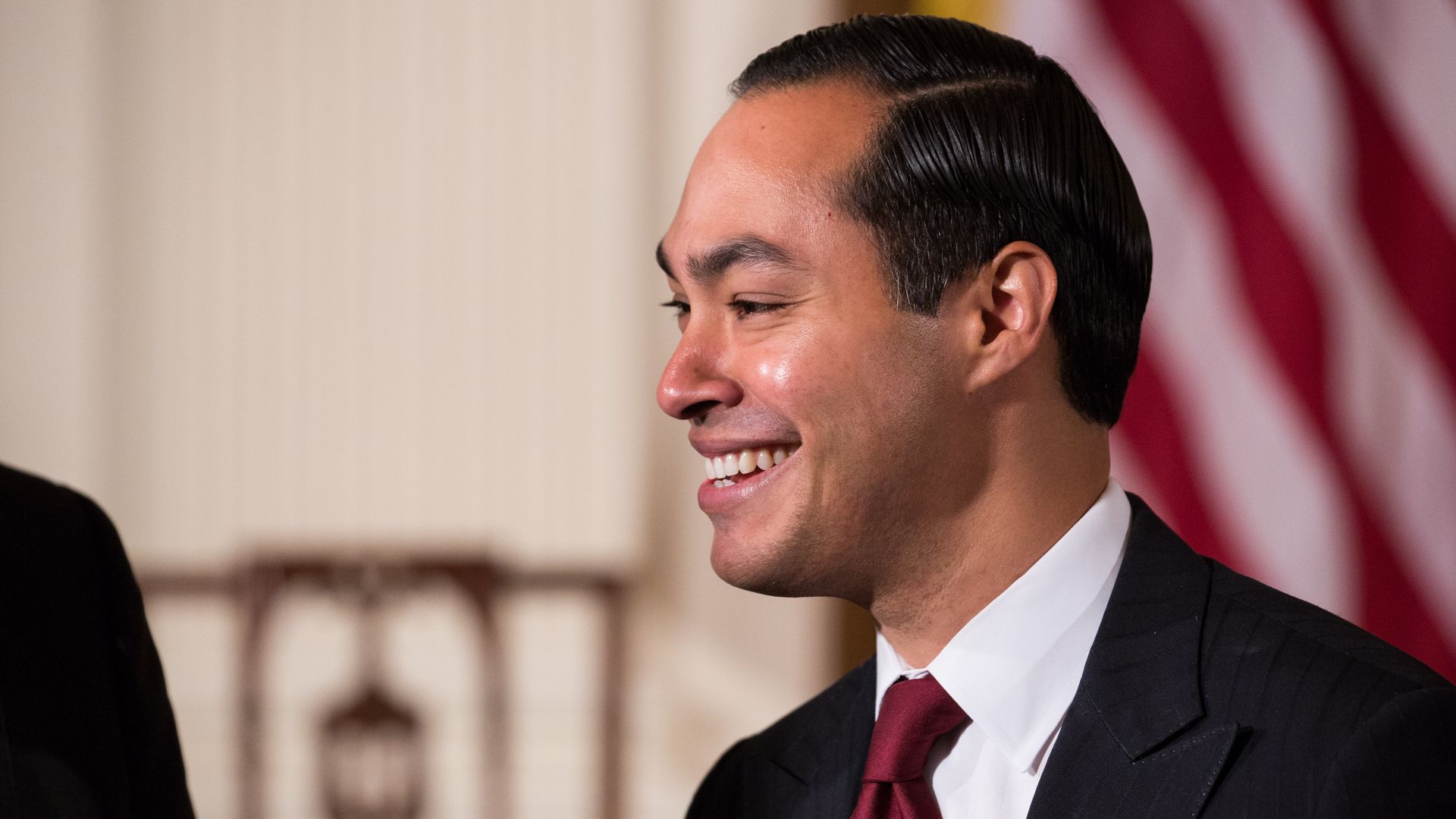 Julian Castro smiling on stage with suit and tie. 