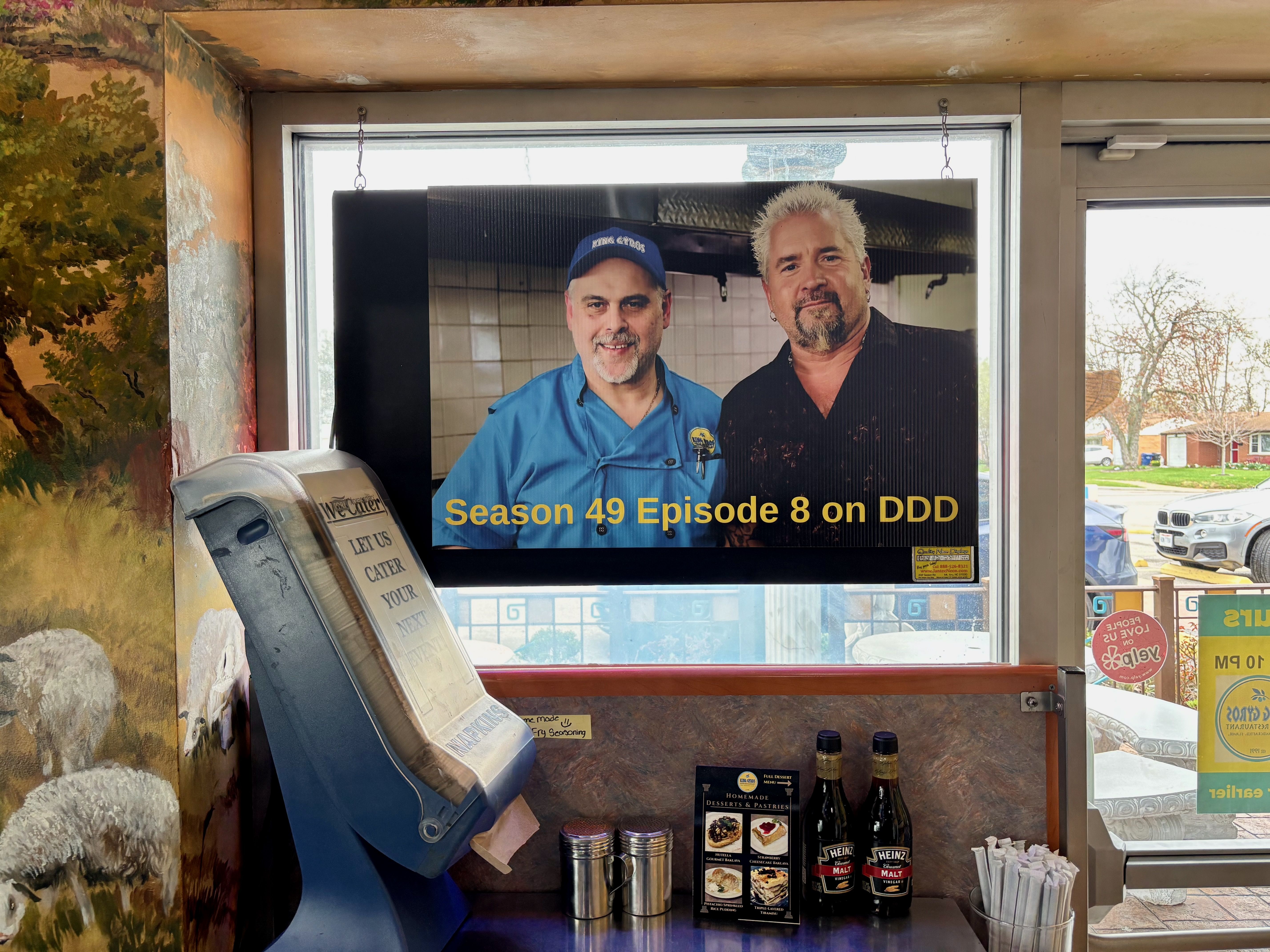 A photo of King Gyros owner Yianni Chalkias and Guy Fieri that says "season 49 episode 8 on DDD"