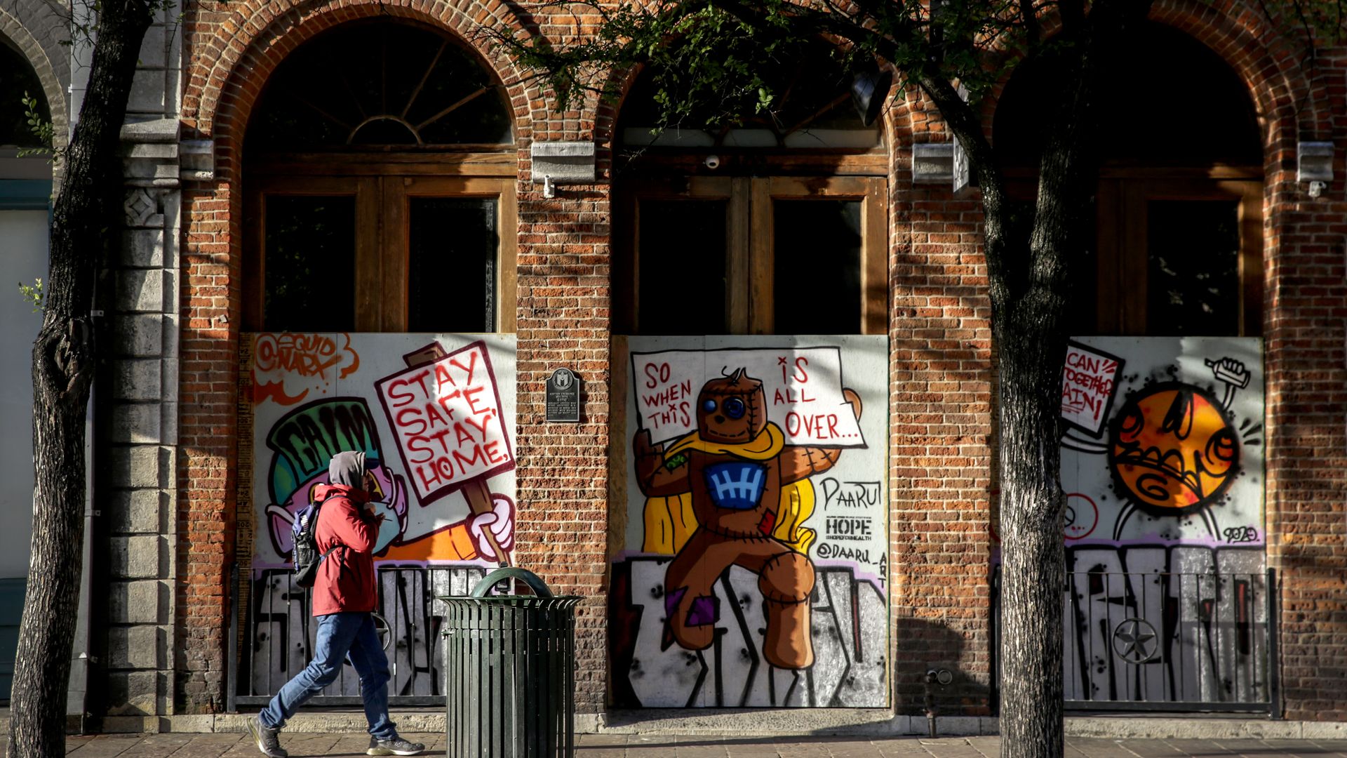 A pedestrian walks by boarded-up businesses on Sixth Street in Austin.