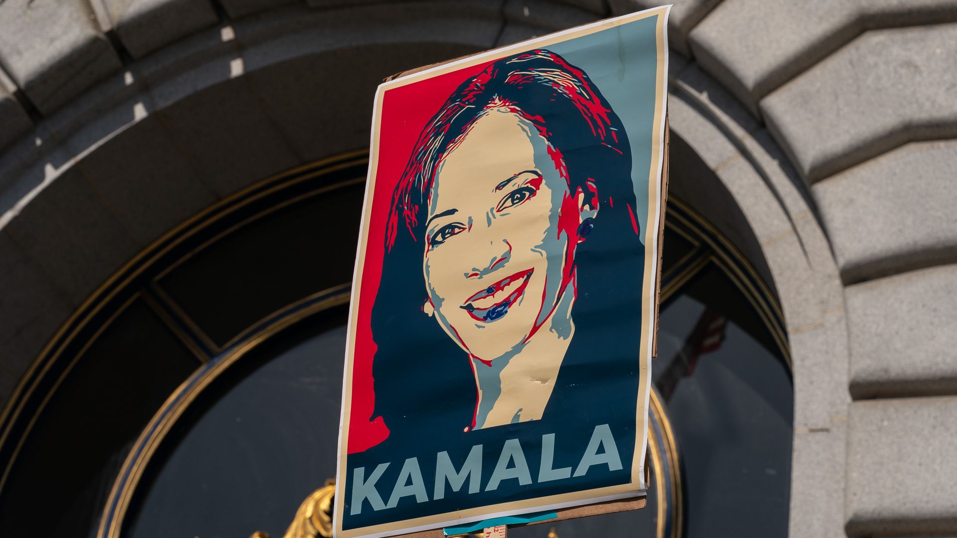 A sign of Kamala Harris' face held up by a supporter 