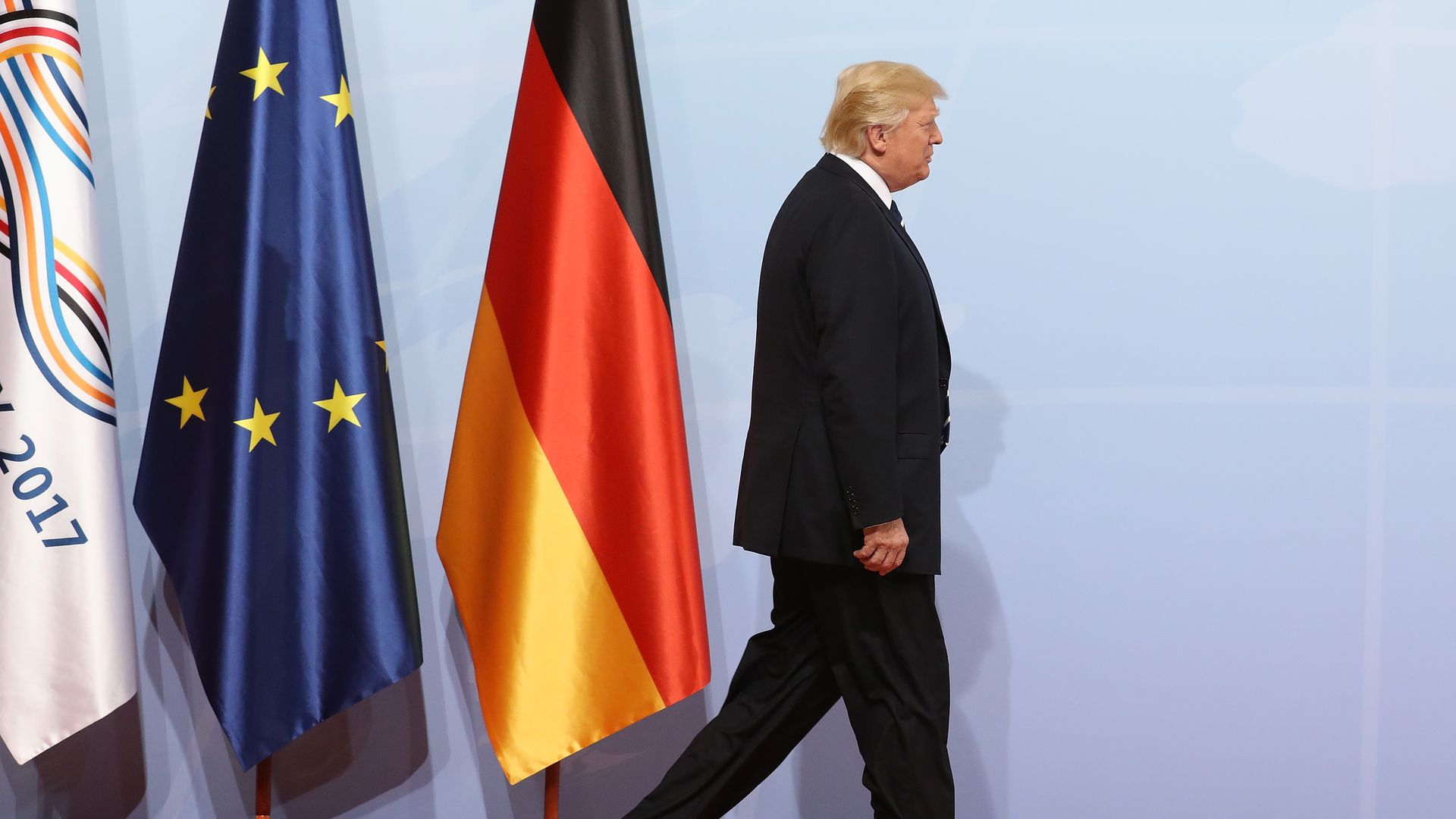 Trump walks past the German and EU flags