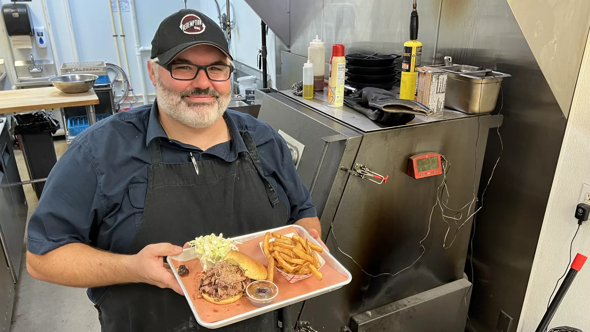 A man holds a tray with bbq food on it