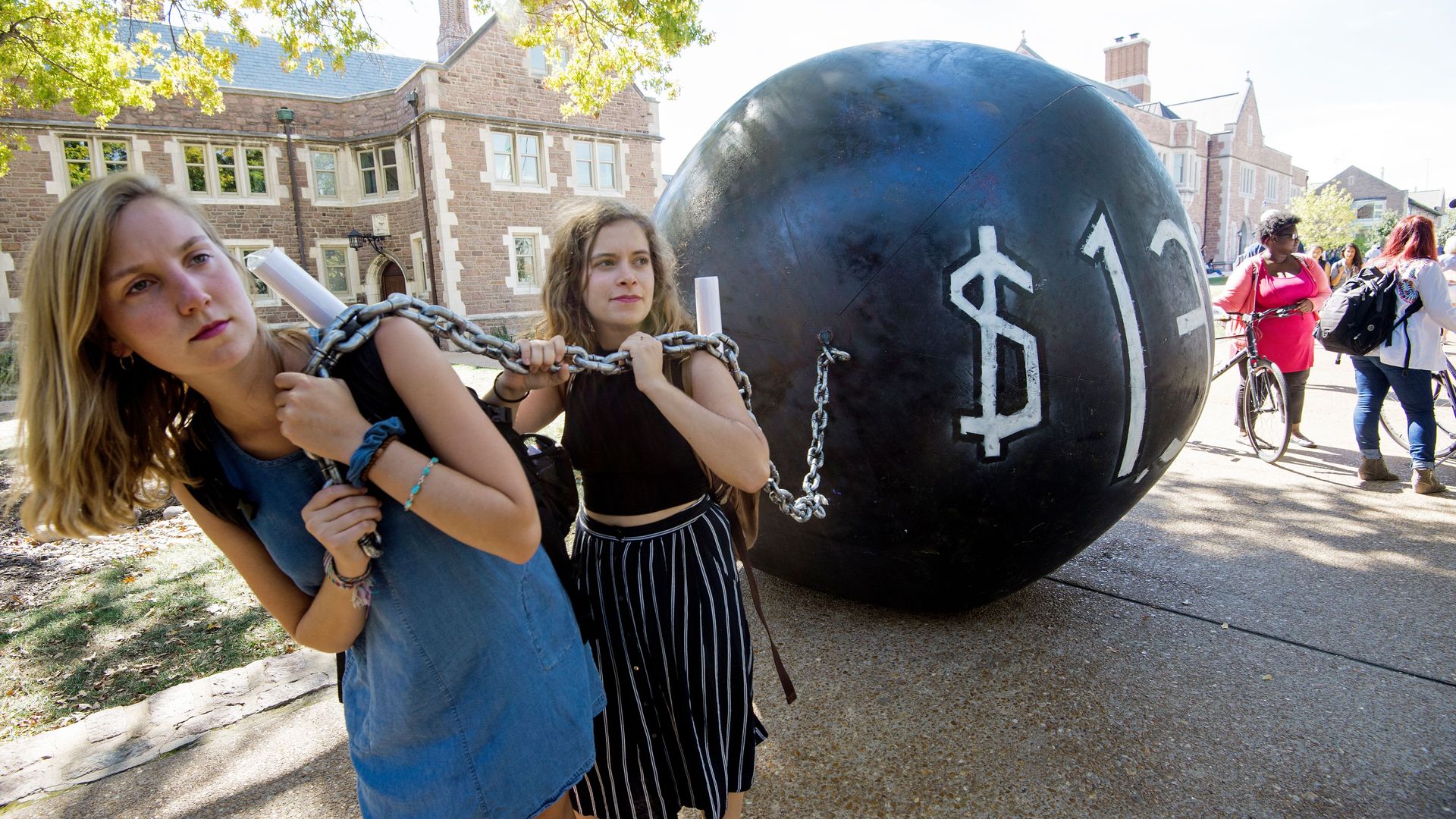 Students pulling a large, fake ball and chain in protest of student debt