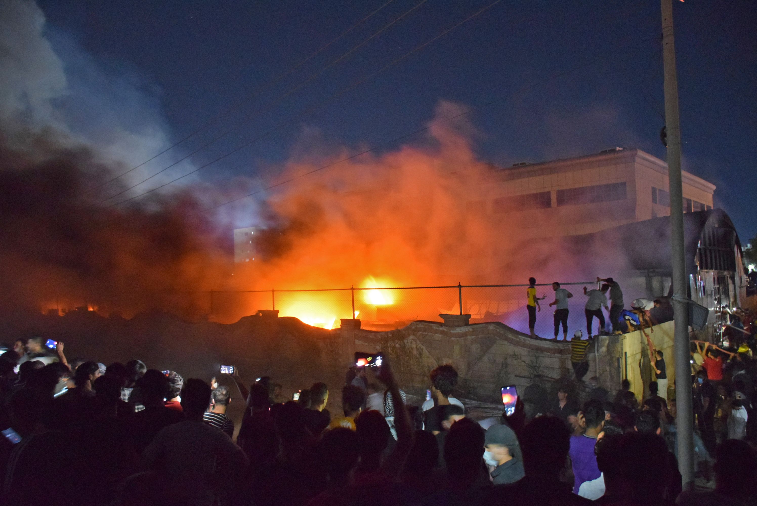 Crowds gather around the burning coronavirus isolation ward of Al-Hussein hospital